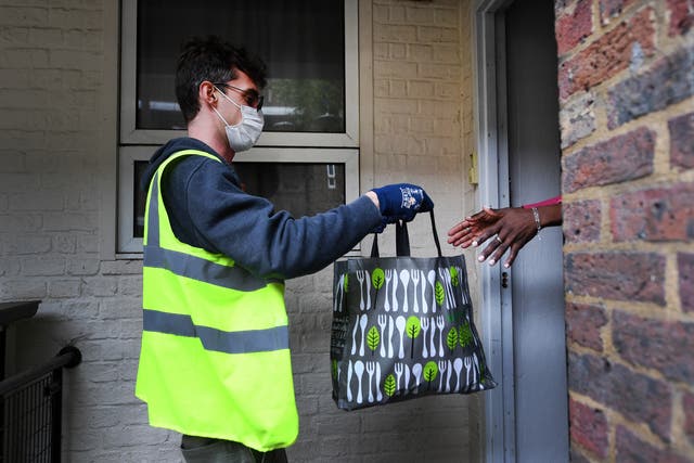 <p>A food bank worker provides assistance to a householder hit economically by coronavirus</p>
