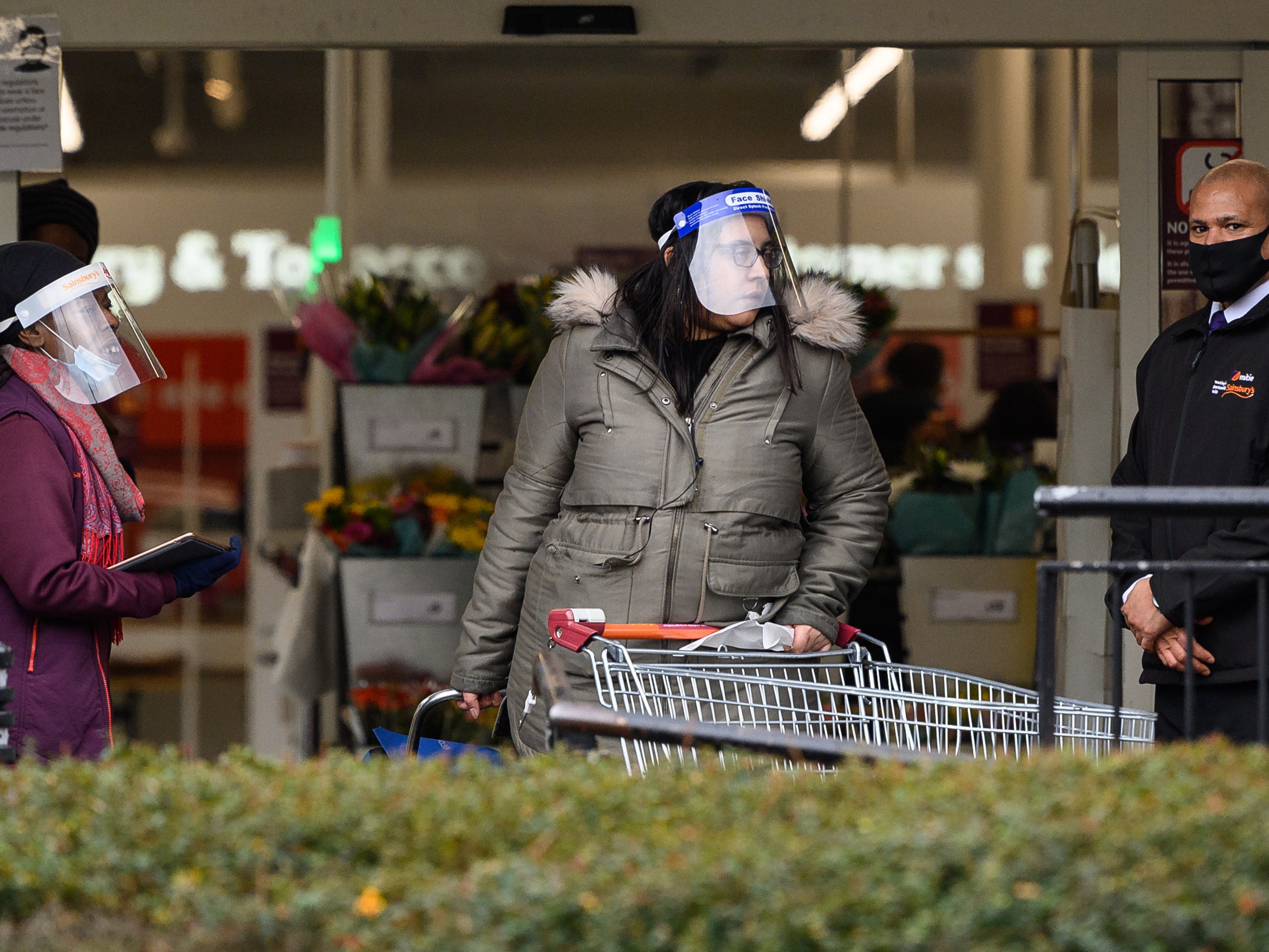 A security guard assists a member of the store team as they stand at the entrance to a branch of Sainsbury’s following the company’s decision to enforce the mandatory wearing of face masks