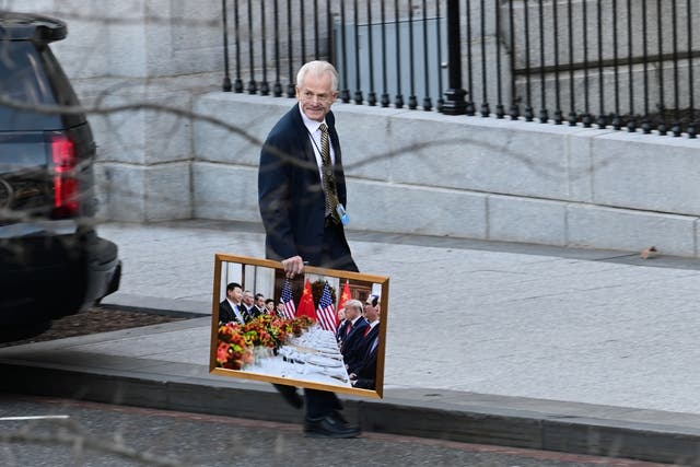 <p>White House adviser Peter Navarro leaves the West Wing with a photograph of U.S. President Trump and Chinese President Xi in Washington</p>