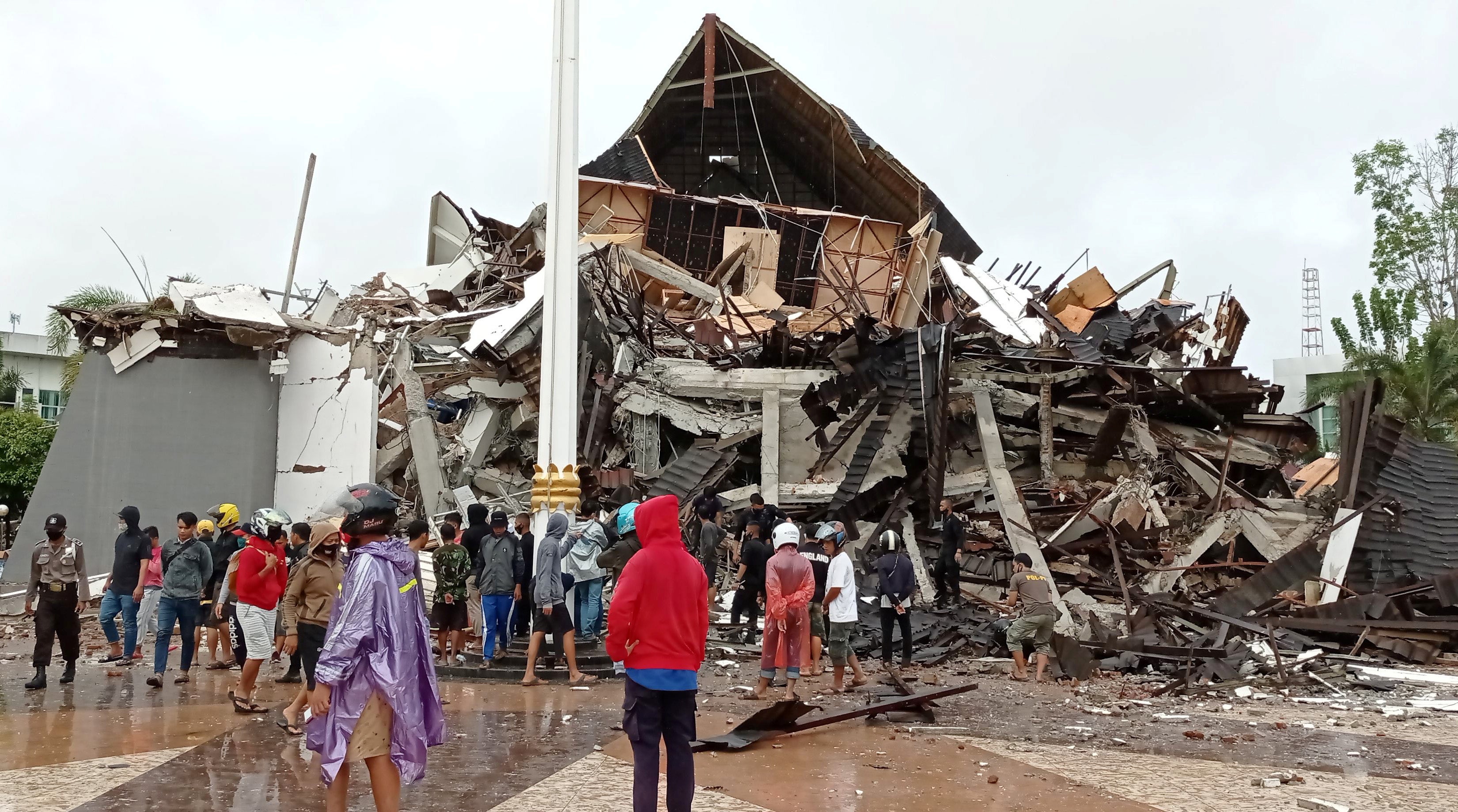 <p>People look at the damaged province’s office of governor of West Sulawesi following an earthquake in Mamuju</p>