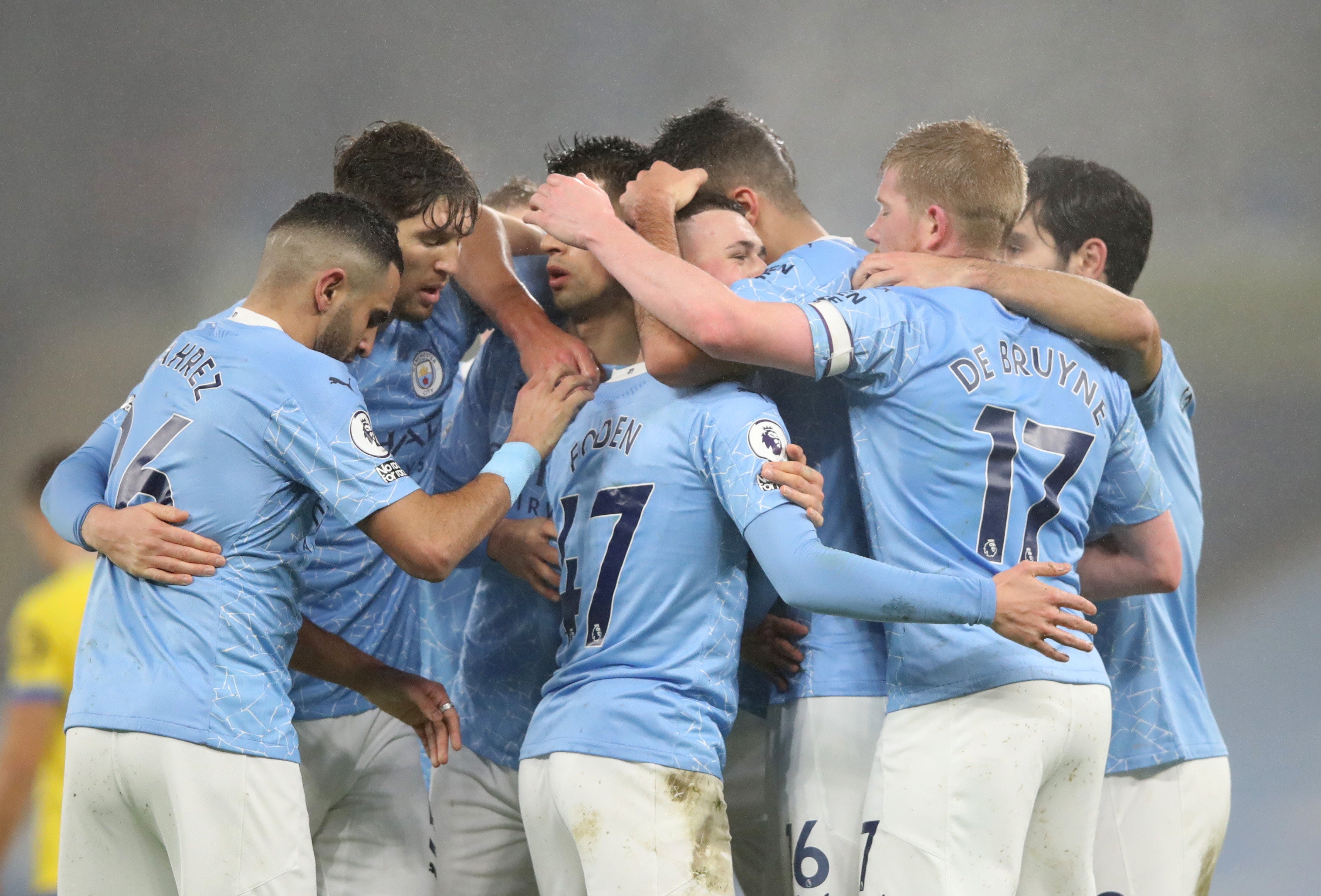 Manchester City players celebrate with a group embrace