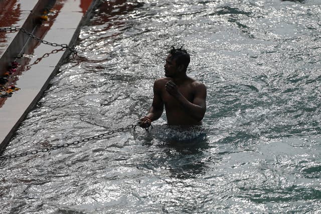 <p>A Hindu devotee takes a holy dip in the waters of the River Ganges during Makar Sankranti, a day considered to be of great religious significance in the Hindu mythology, on the first day of the religious Kumbh Mela festival in Haridwar on 14 January 2021</p>