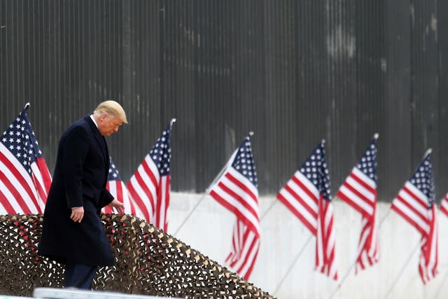 President Donald Trump walks down the steps before a speech near a section of the US Mexico border wall