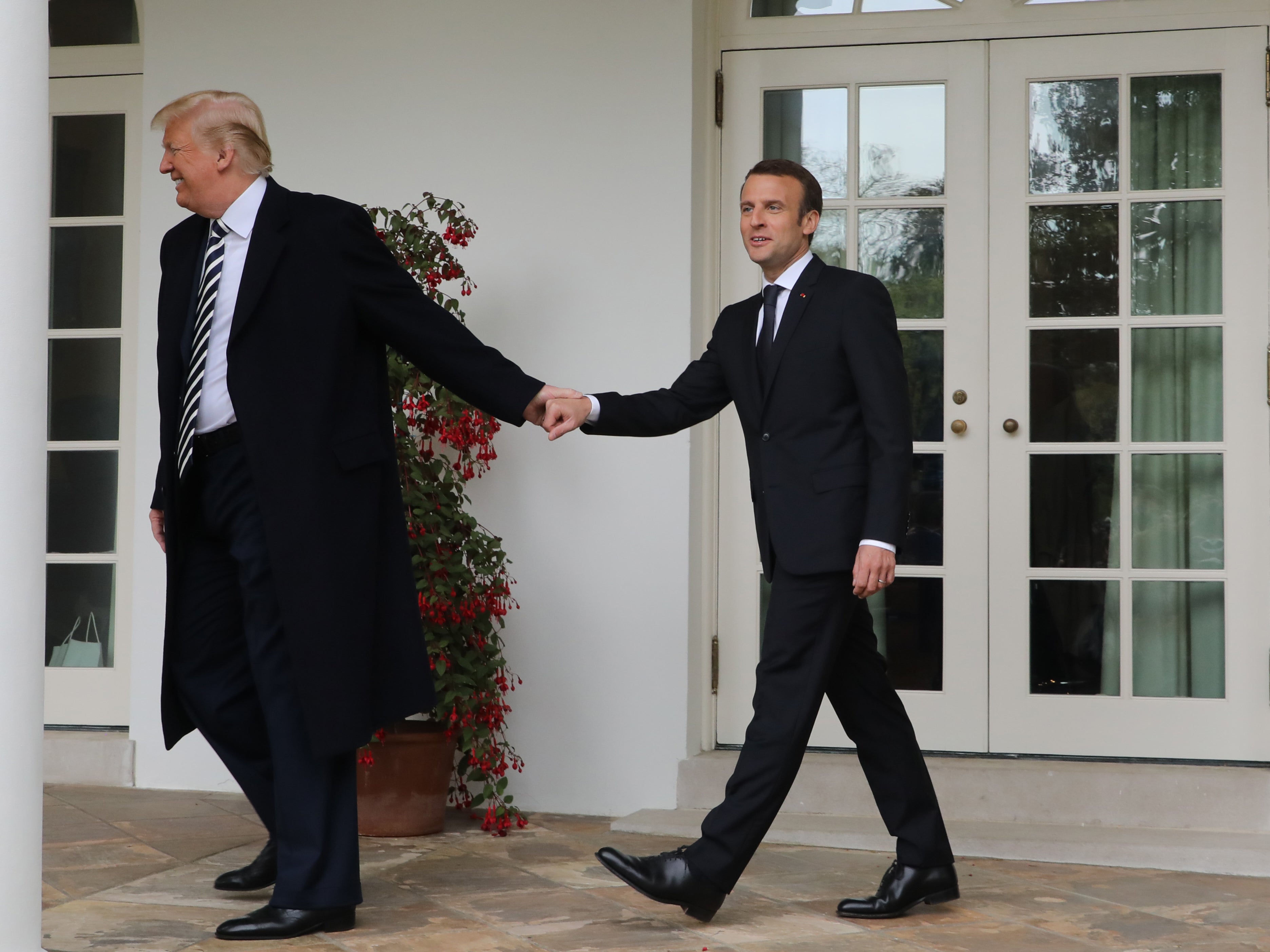 French President Emmanuel Macron and Donald Trump walk hand in hand under the colonnades of the White House in Washington on 24 April 2018