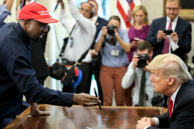 <p>Kanye West muestra una foto en un teléfono a Donald Trump durante una reunión en la oficina Oval</p>