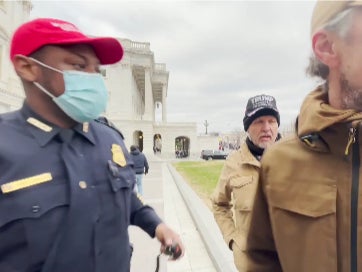 Capitol Police officer Lt. Tarik Khalid Johnson wearing a red MAGA hat trying to recruit Trump supporters to help him gain control of the crowd during the Capitol insurrection on 6 January 2021.