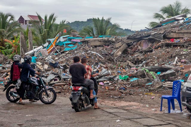 <p>Unas personas observan el sábado 16 de enero de 2021 los escombros de un edificio que colapsó luego de un sismo en Mamuju, Célebes Occidental, en Indonesia.&nbsp;</p>