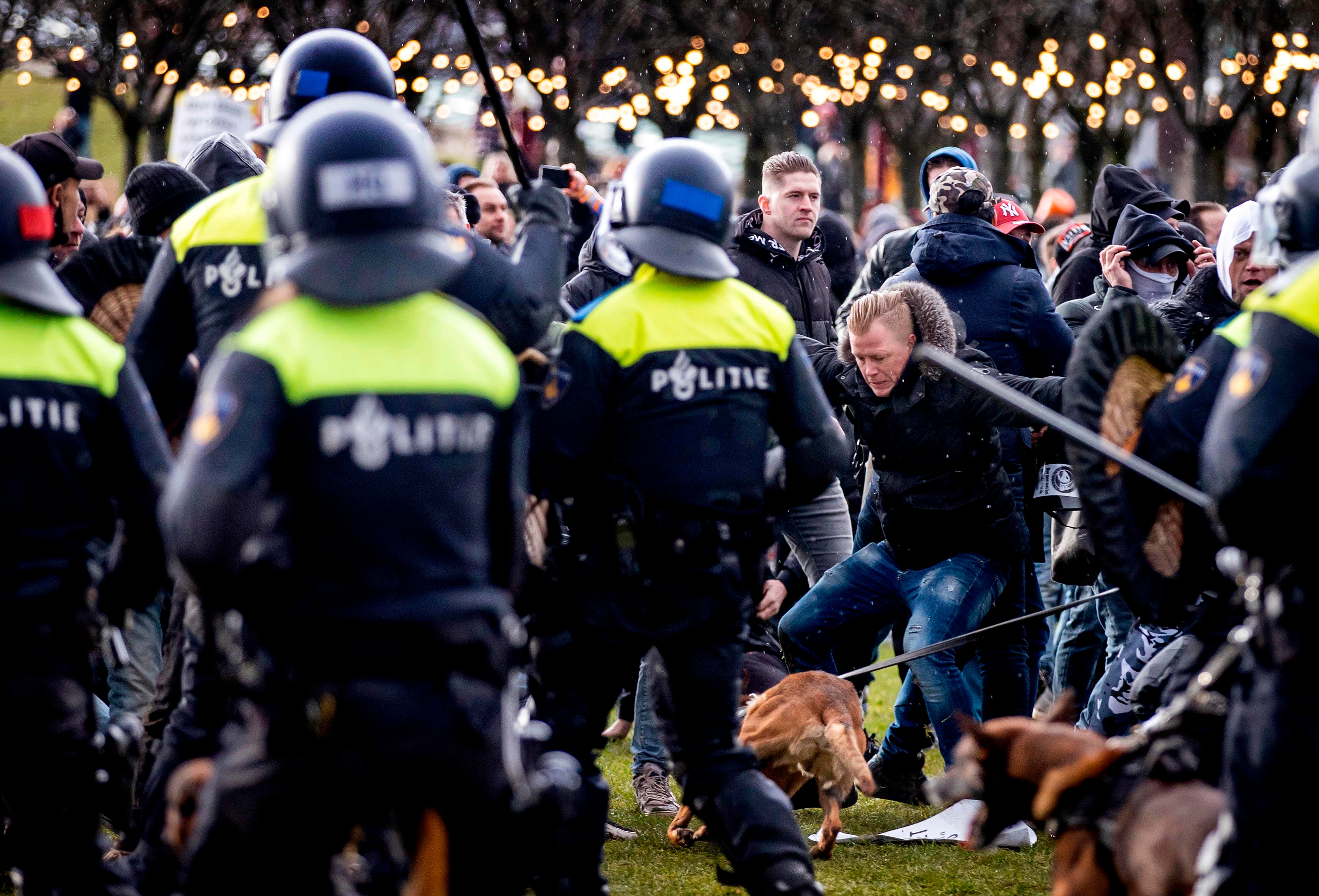 Demonstrators face Dutch police at the Museumplein, in Amsterdam, on January 17, 2021