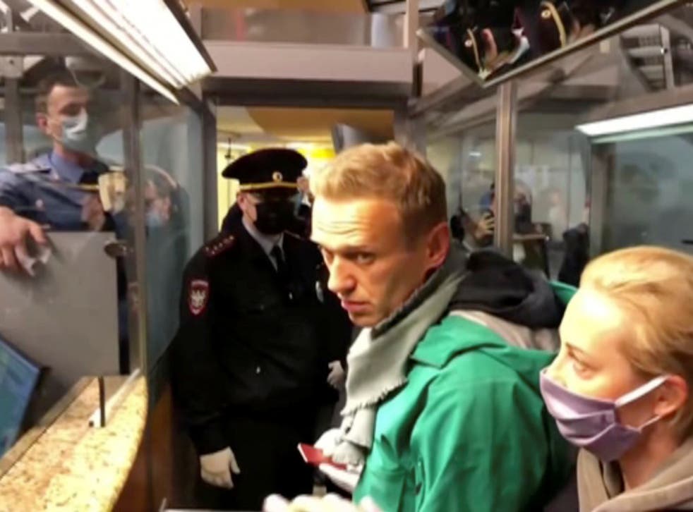A still image taken from video footage shows law enforcement officers speaking with Russian opposition leader Alexei Navalny before leading him away at Sheremetyevo airport in Moscow, Russia
