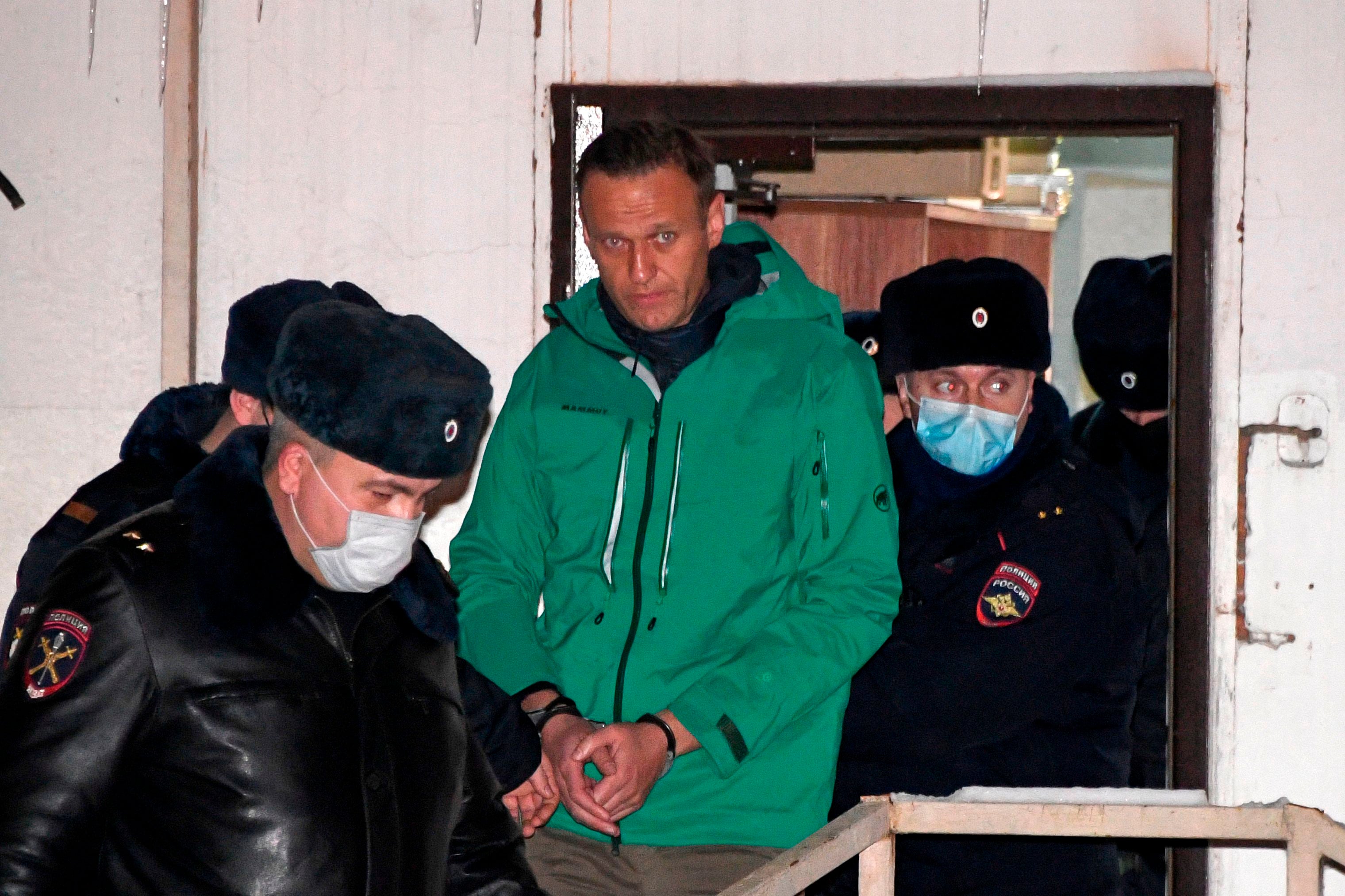 Alexei Navalny is escorted out of a police station following the court ruling that ordered him to be jailed for 30 days