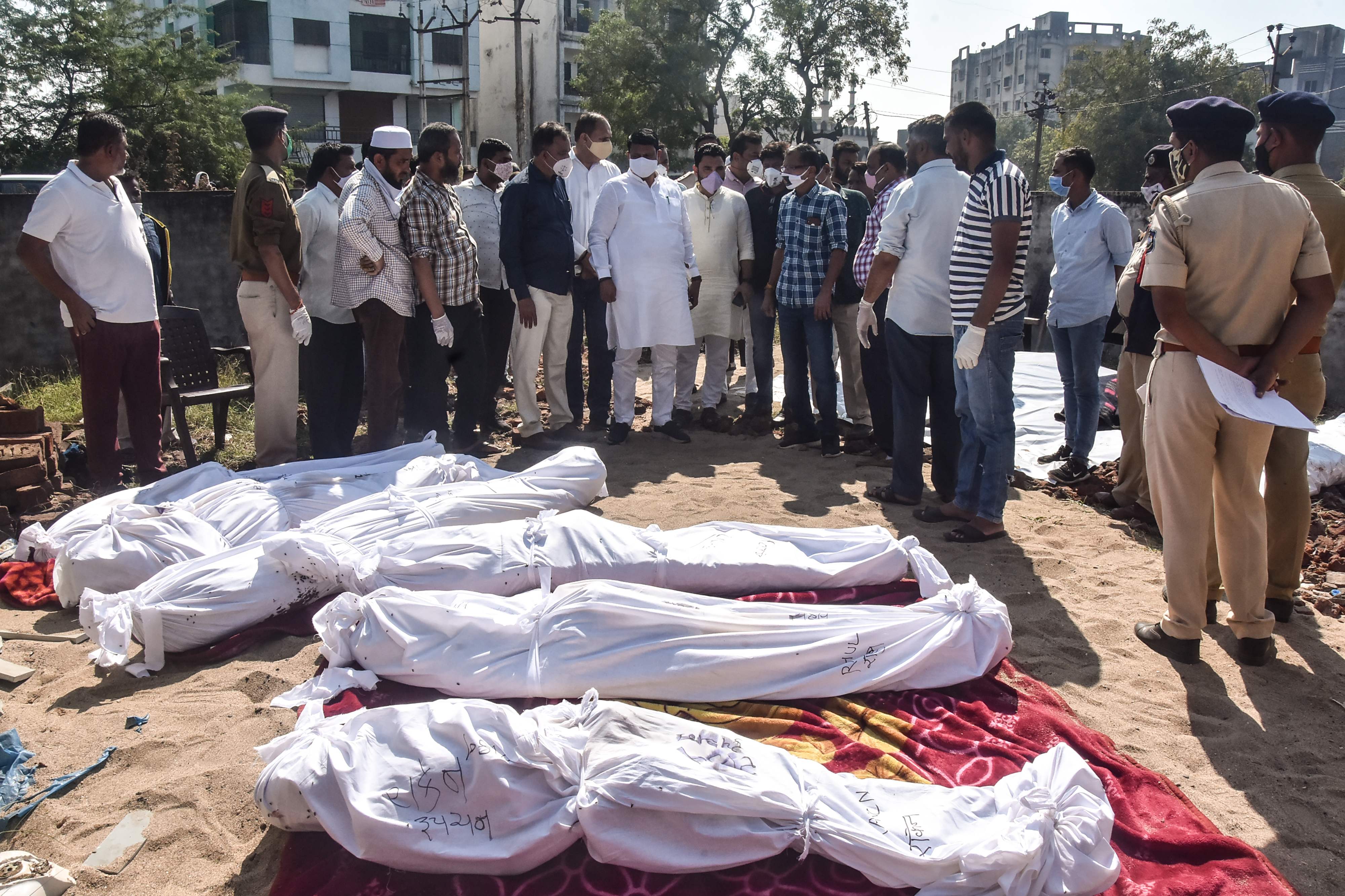 Police personnel and residents gather around the bodies of victims after a truck lost control and ran over them while sleeping in Surat district.
