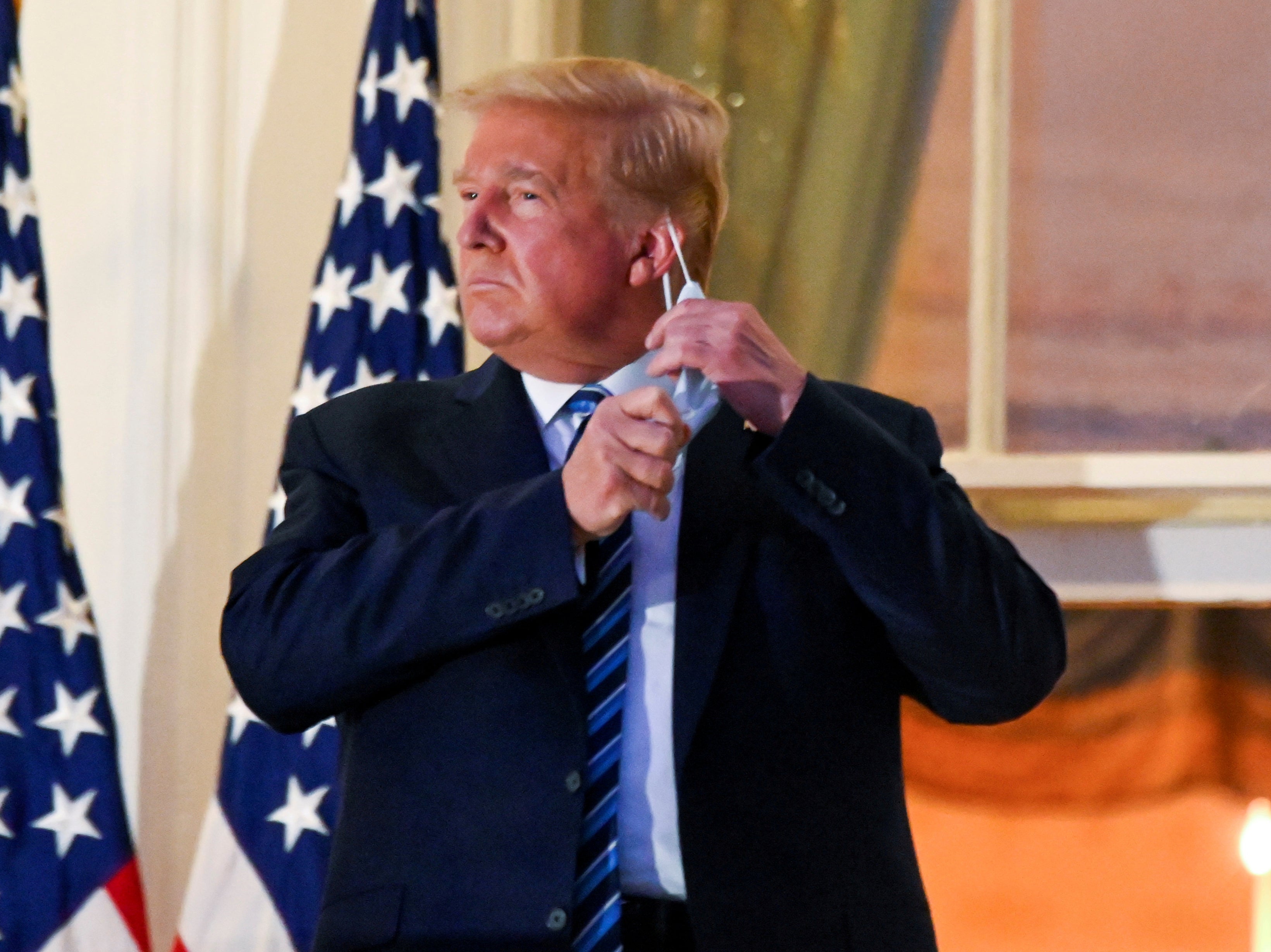 Donald Trump pulls off his protective face mask at the White House after returning from Covid treatment at Walter Reed Medical Center on 5 October, 2020