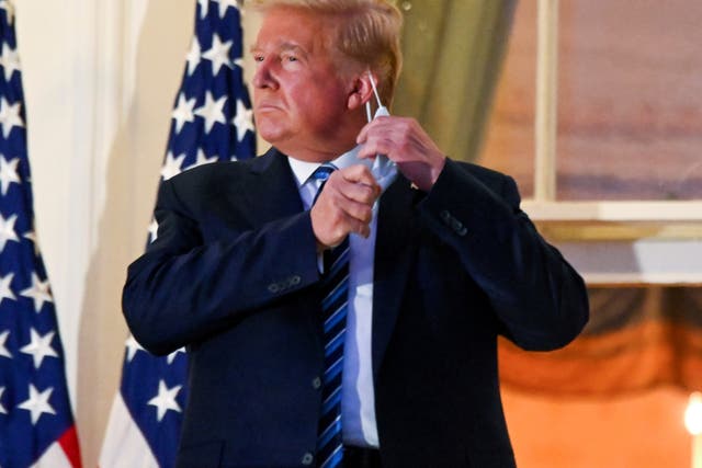 Donald Trump pulls off his protective face mask at the White House after returning from Covid treatment at Walter Reed Medical Center on 5 October, 2020
