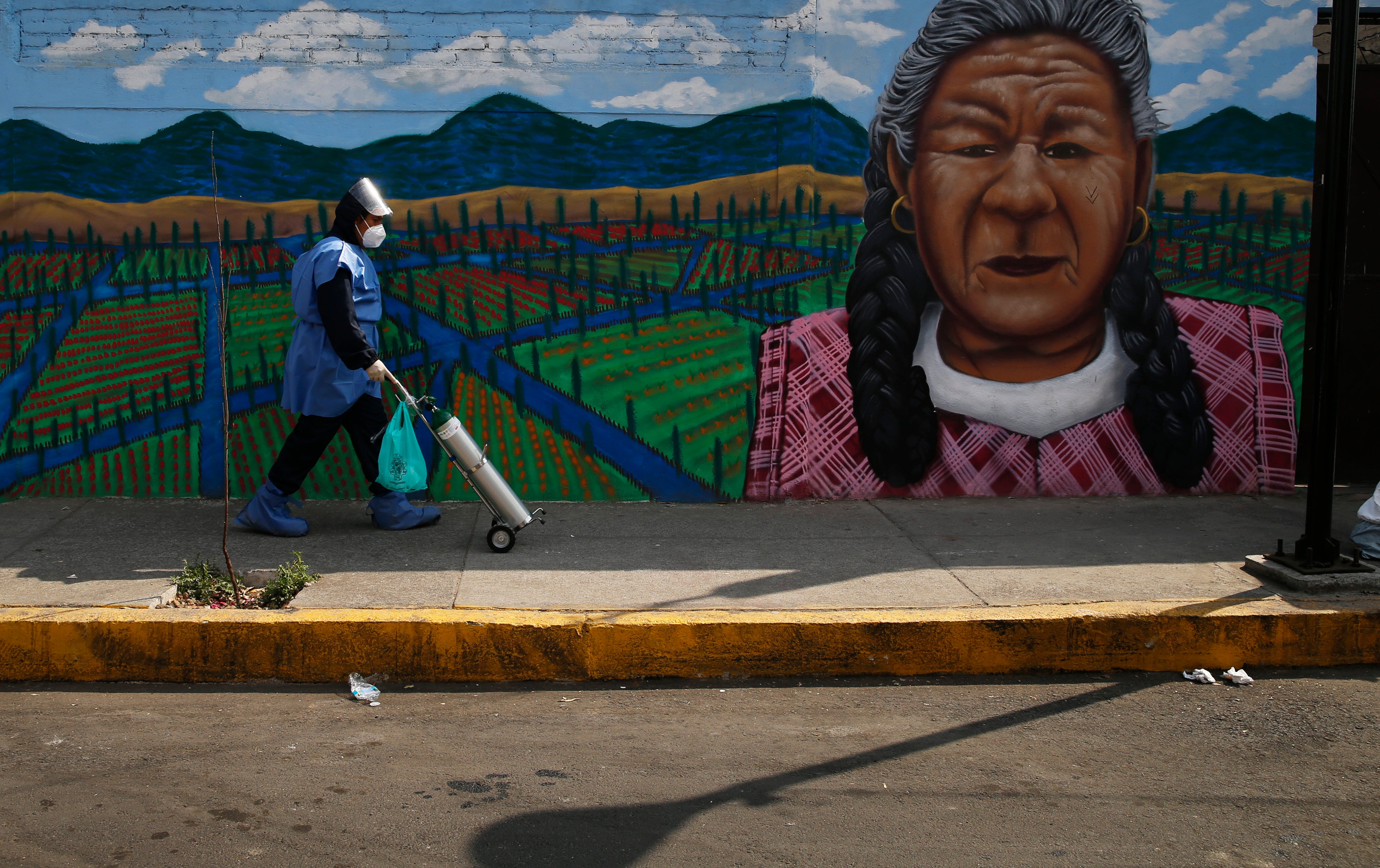 <p>Alexis Hernández entrega un tanque de oxígeno a un paciente con COVID-19, en la alcaldía de Iztapalapa, en la Ciudad de México.&nbsp;</p>