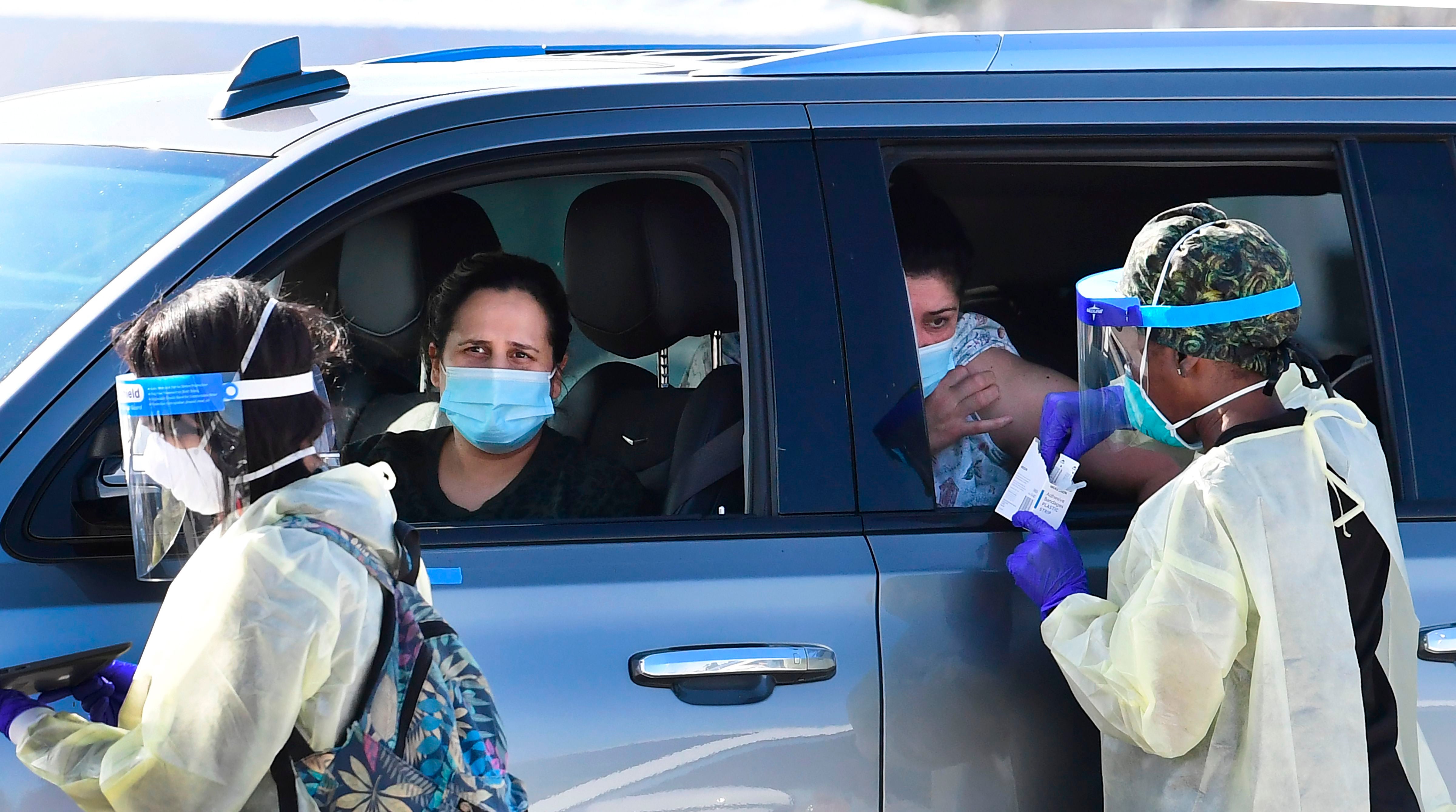 <p>People pull up in their vehicles for Covid-19 vaccines in the parking lot of The Forum in Inglewood, California</p>
