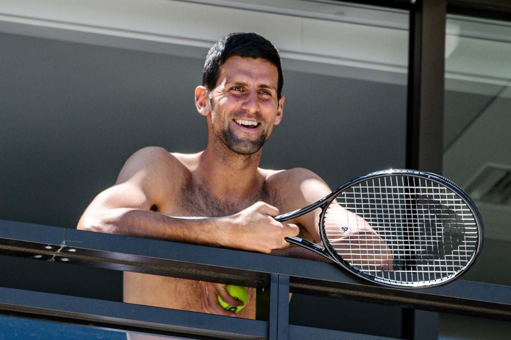 Novak Djokovic smiles at fans from a hotel balcony in Adelaide