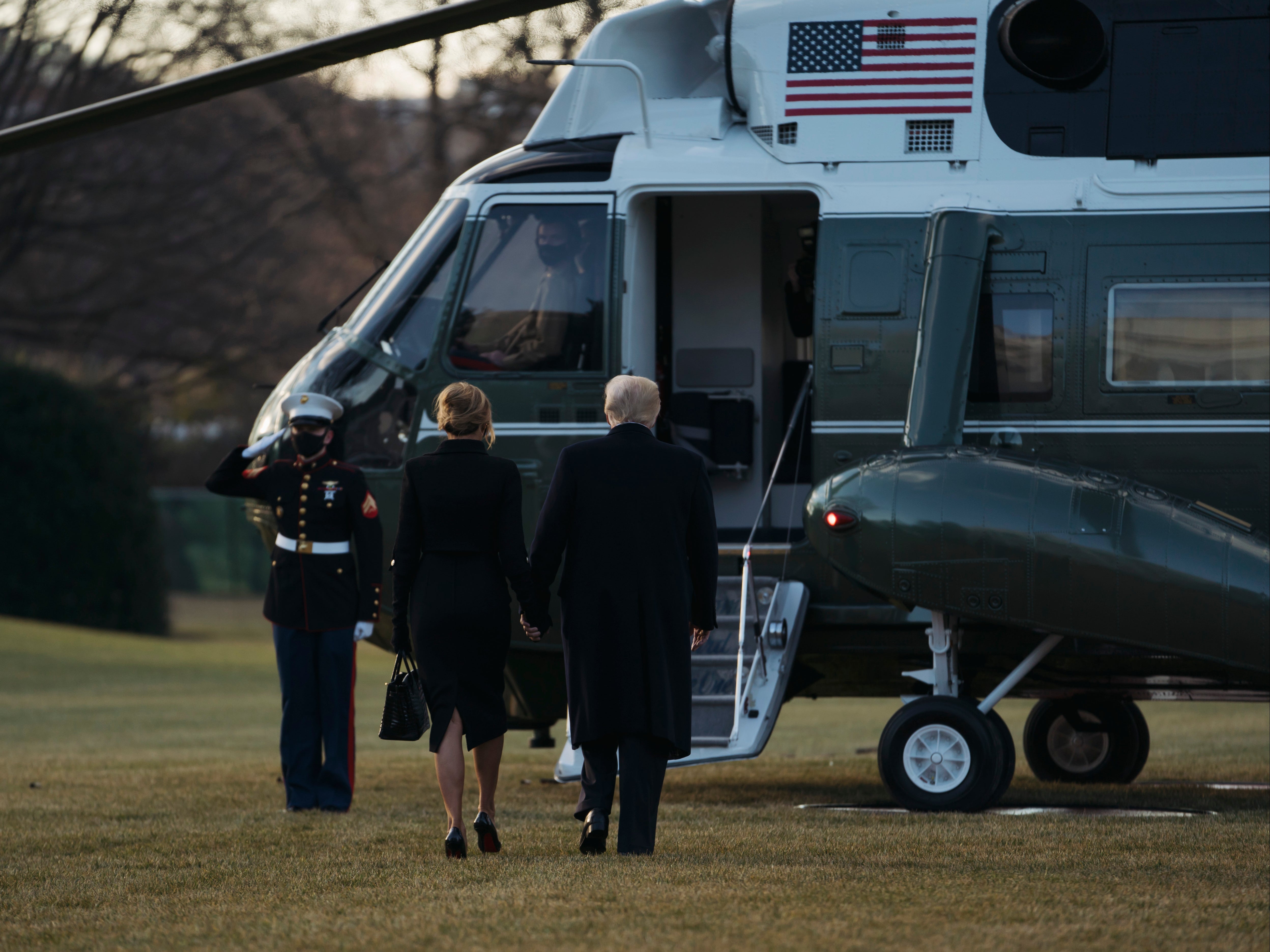 Donald Trump and Melania Trump hold hands as they prepare to depart the White House on Marine One to Florida several hours ahead of the inauguration ceremony. Mr Trump is the first president in more than 150 years to refuse to attend their successor's inauguration