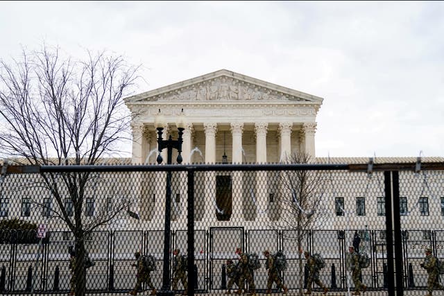 <p>National Guard troops walk behind fencing in front of the US Supreme Court as security tightens ahead of presidential inaugural events on Capitol Hill in Washington, DC</p>