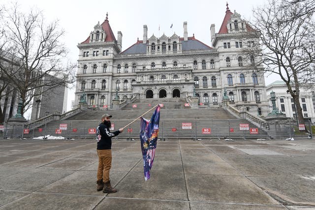 <p>Trump supporter Mark Leggiero, of Florida, N.Y., holds a banner outside the New York state Capitol objecting the inauguration of President Joe Biden on Wednesday 20 January 2021, in Albany, N.Y</p>