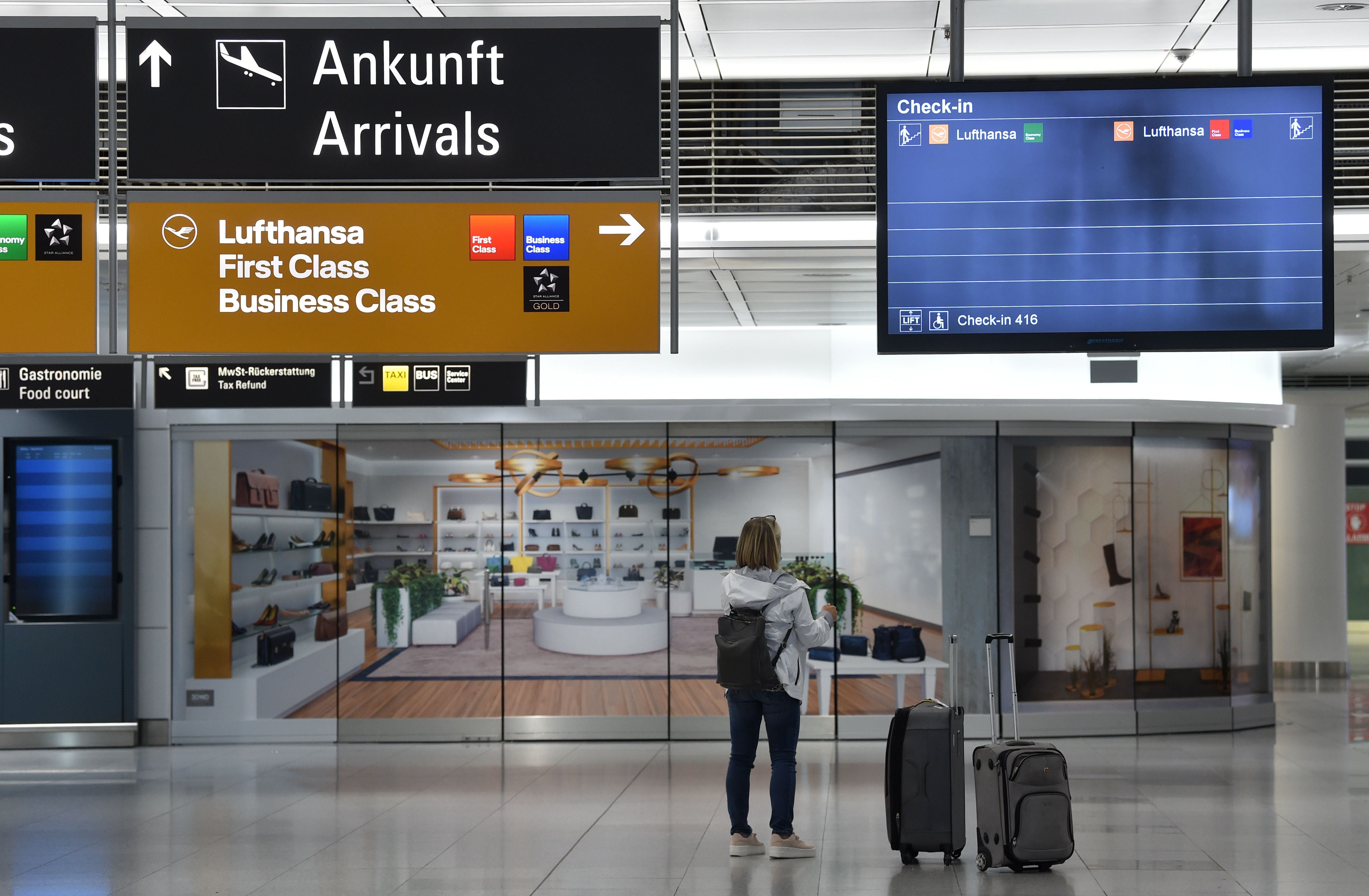 A passenger stand in front of a check-in screen at the “Franz-Josef-Strauss” airport in Munich. Germany has warned it will have to close its borders to prevent the new variant