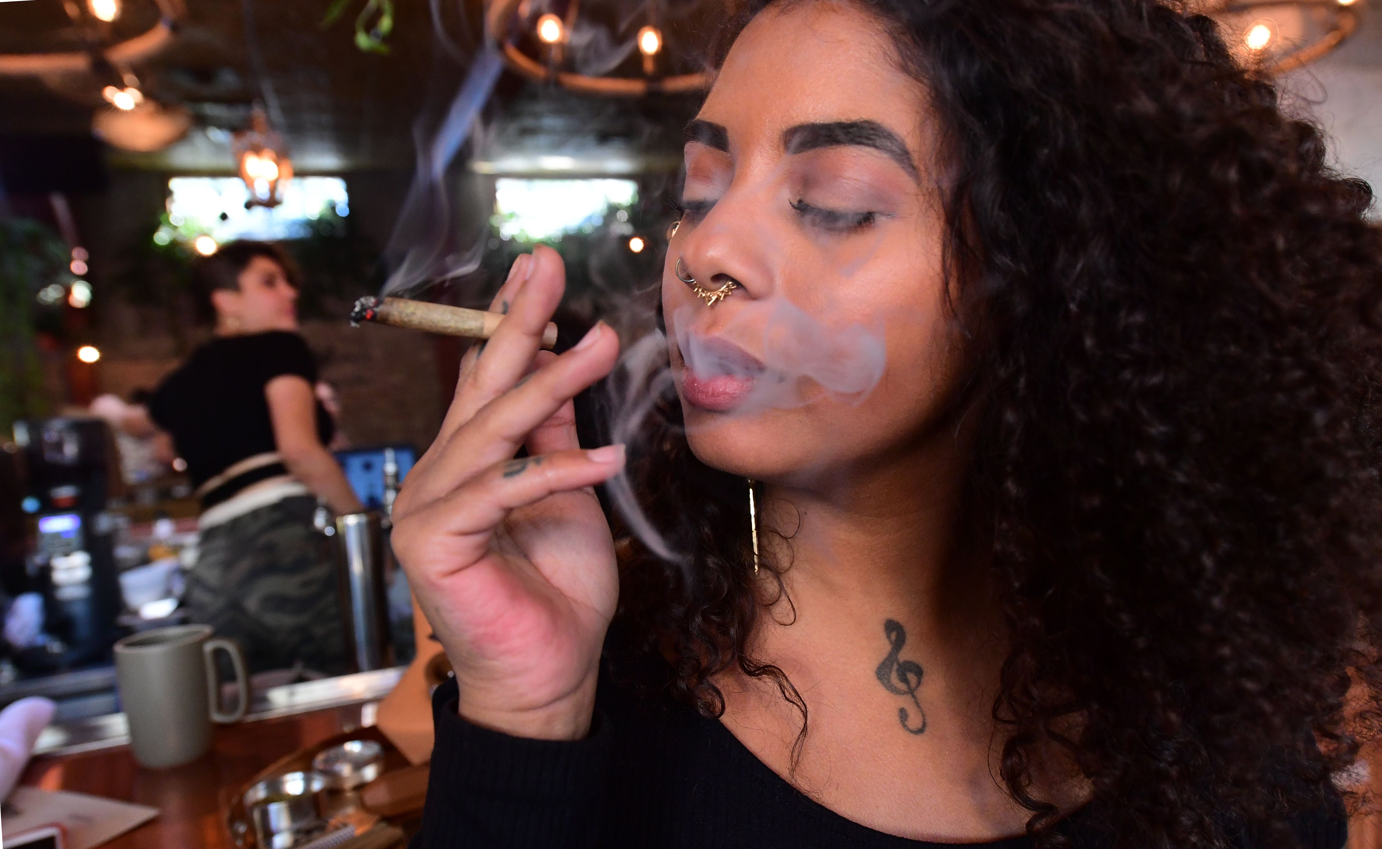 Kush Doleo smokes a joint at the Lowell Cafe in West Hollywood, which offers diners an array of weed products
