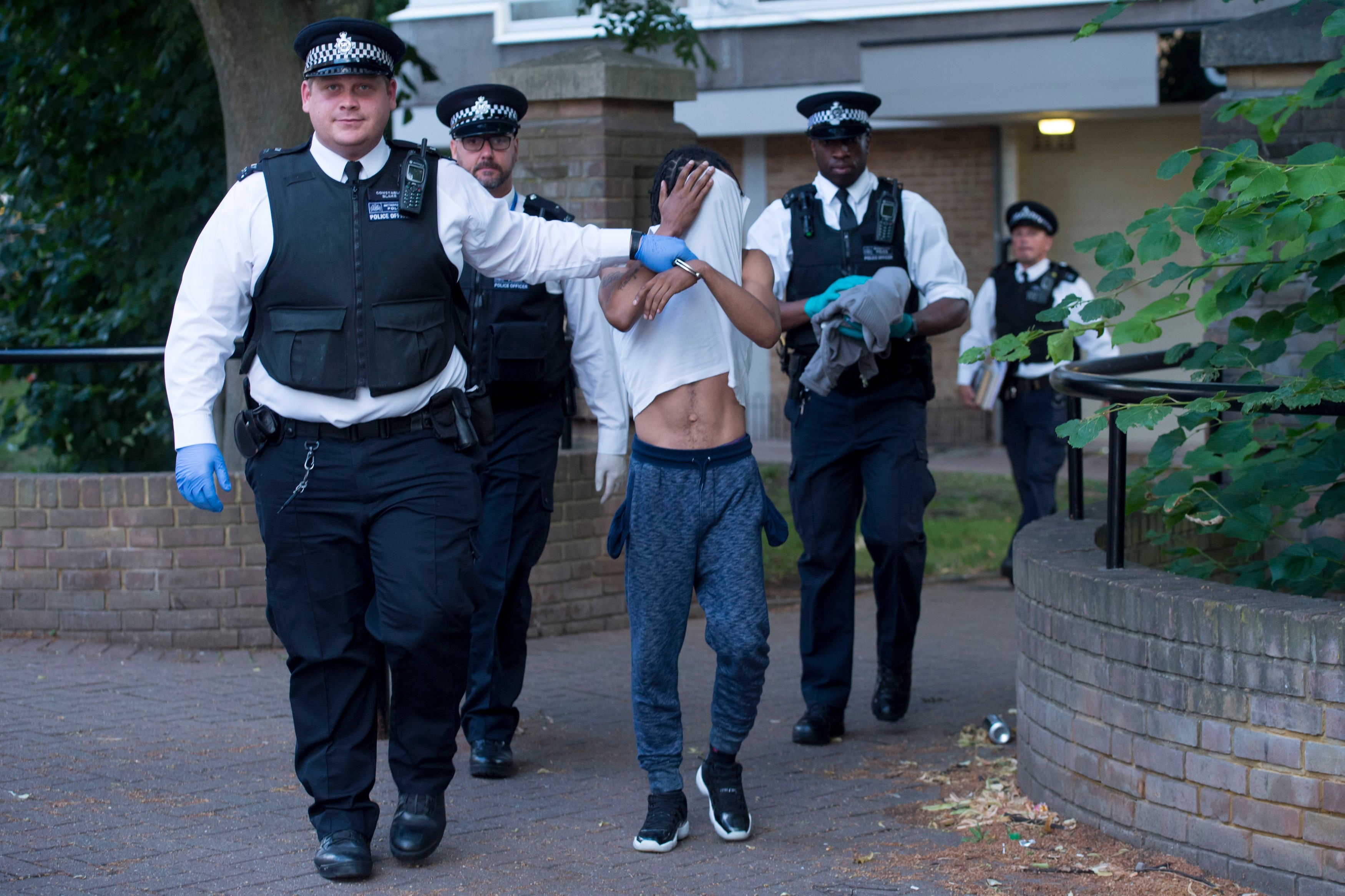 A person is led away after a number of drug raids on a housing estate in south London