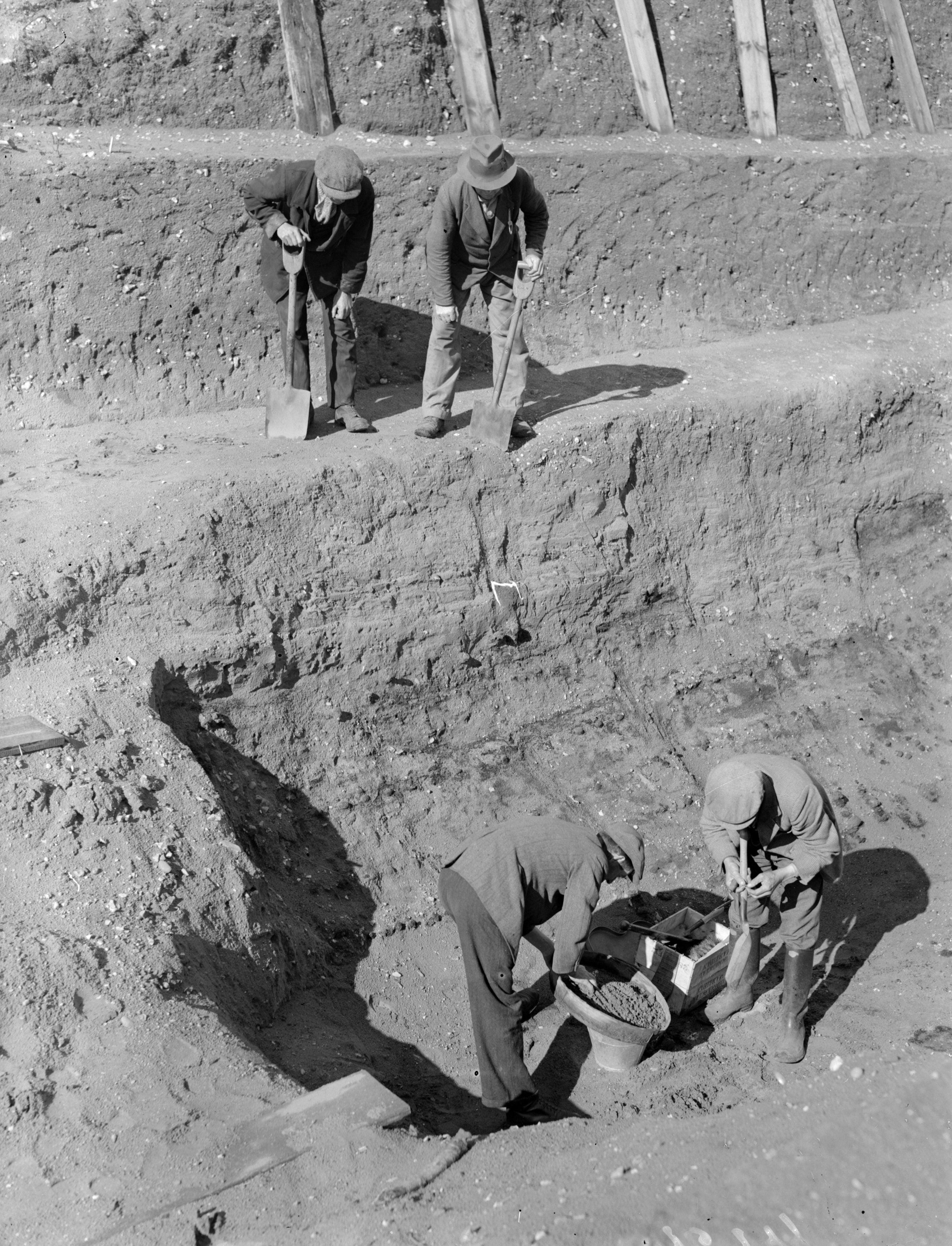 Workmen sift through earth at the bottom of the excavation of the Anglo-Saxon burial ship at Sutton Hoo, Suffolk, on 31 July 1939