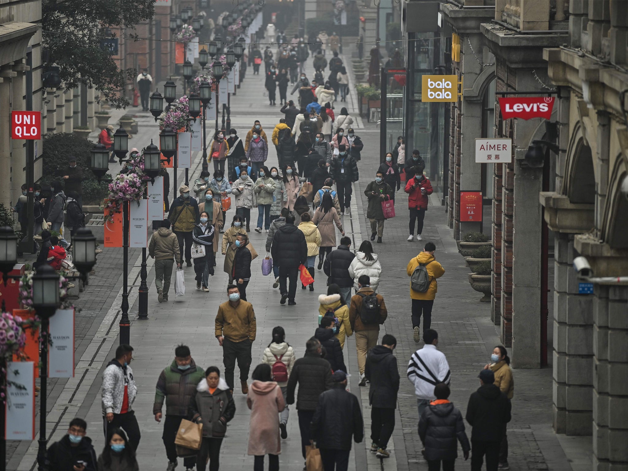 People walking along a pedestrian street in Wuhan on 23 January, 2021, one year after the city went into lockdown to curb the spread of Covid-19