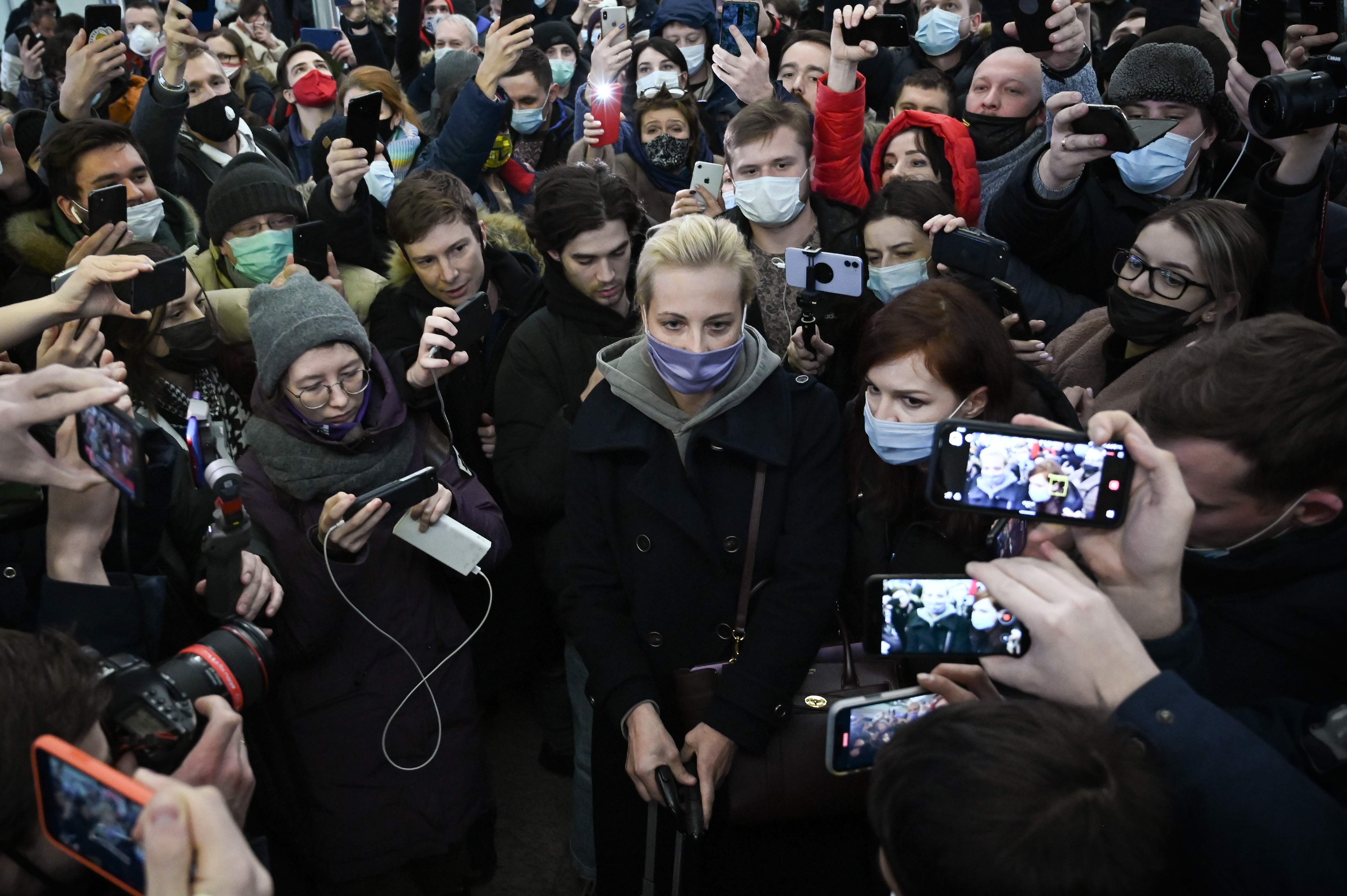 Yulia surrounded by people as she leaves Moscow’s Sheremetyevo airport after her husband’s arrest earlier this month