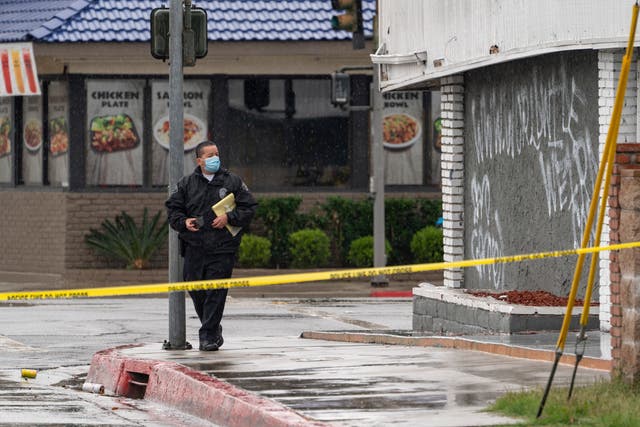 <p>El Monte Police Chief David Reynoso, left, takes pictures of graffiti on the side wall of the First Works Baptist Church, after an explosion in El Monte, California on 23 January 2021.&nbsp;</p>