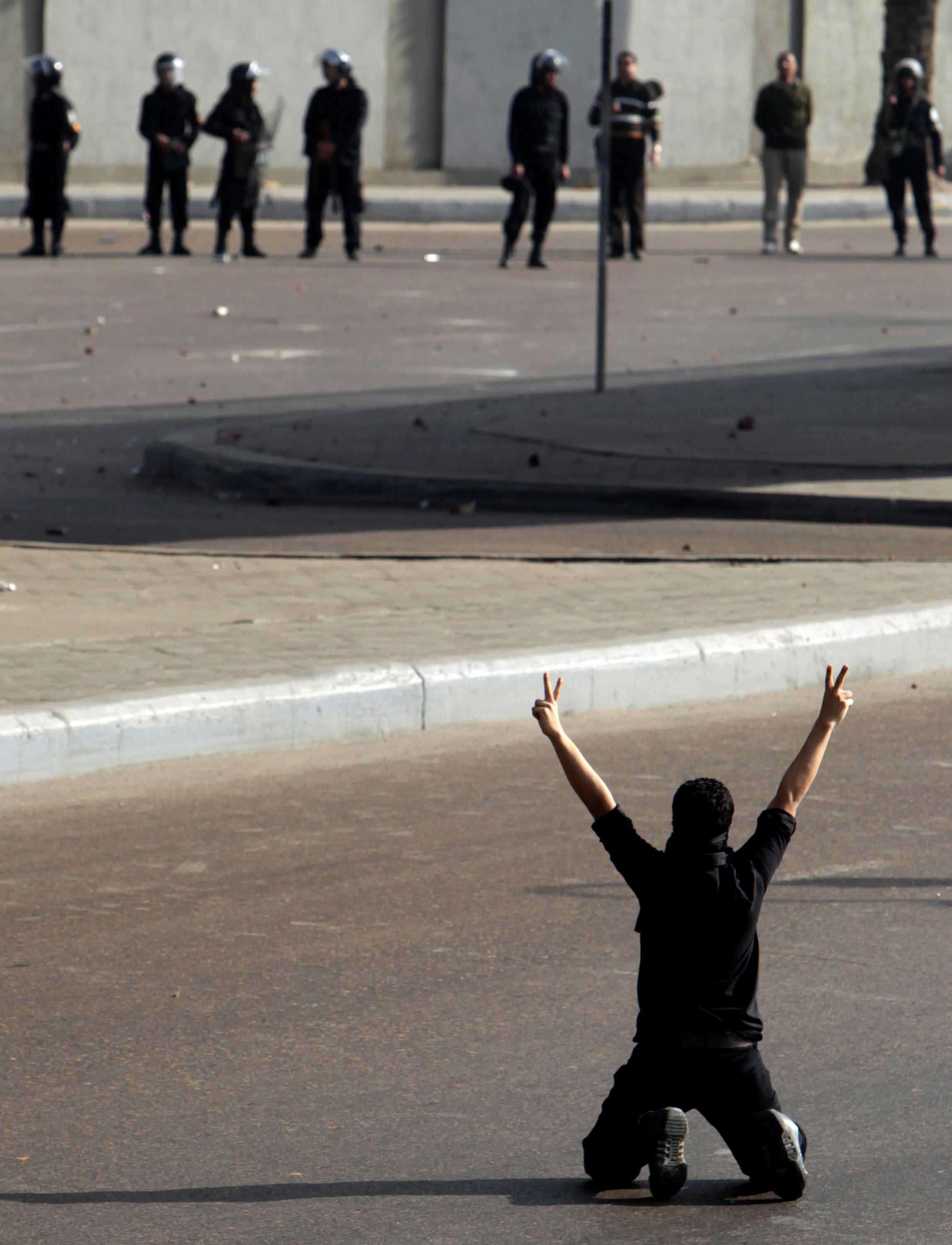 A protester flashes a victory sign in front of police during clashes in Cairo in January 2011
