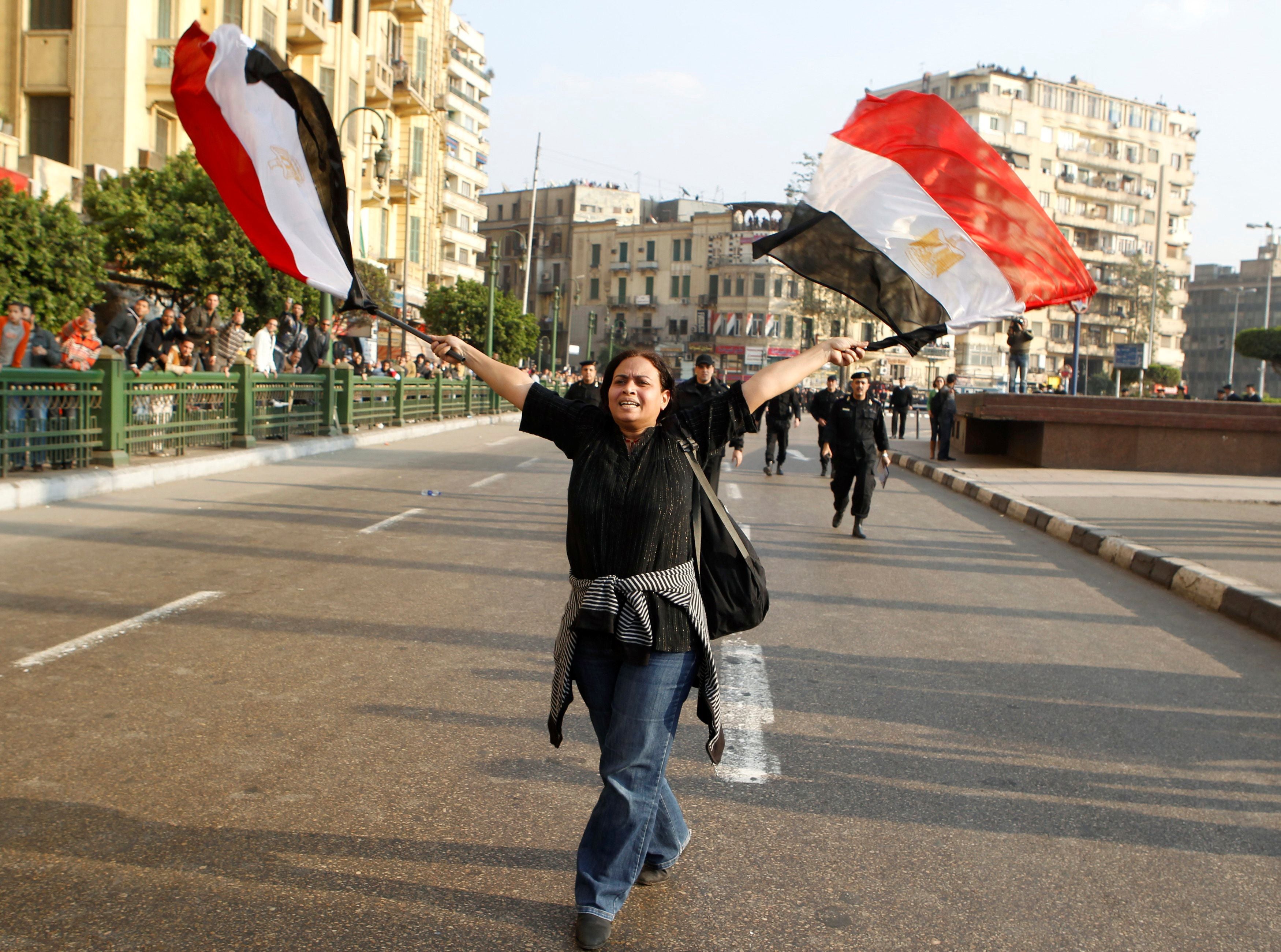 An anti-government protester waves Egyptian flags during clashes with police in downtown Cairo on 25 January 2011.