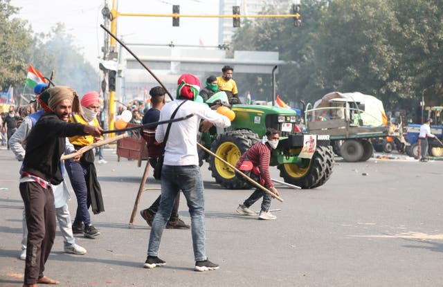 Farmers hold sticks as they confront police officers in Delhi