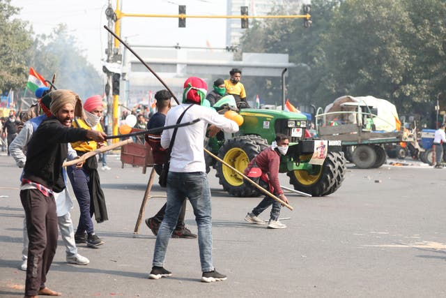 Farmers hold sticks as they confront police officers in Delhi