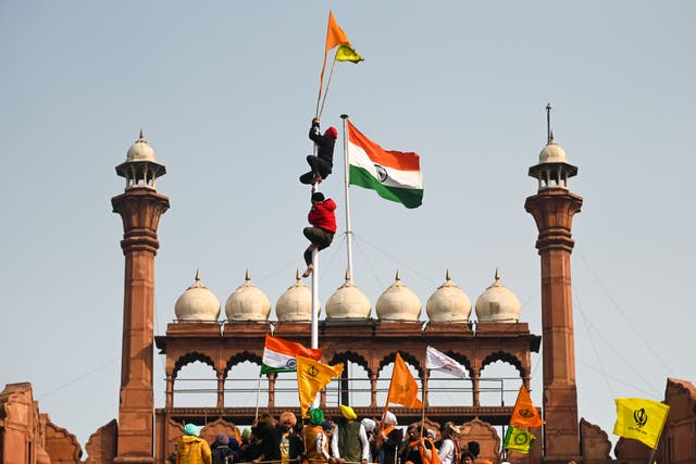 <p>Protesters climb a flagpole at the ramparts of the Red Fort as farmers continue to demonstrate against the central government’s recent agricultural reforms in Delhi</p>