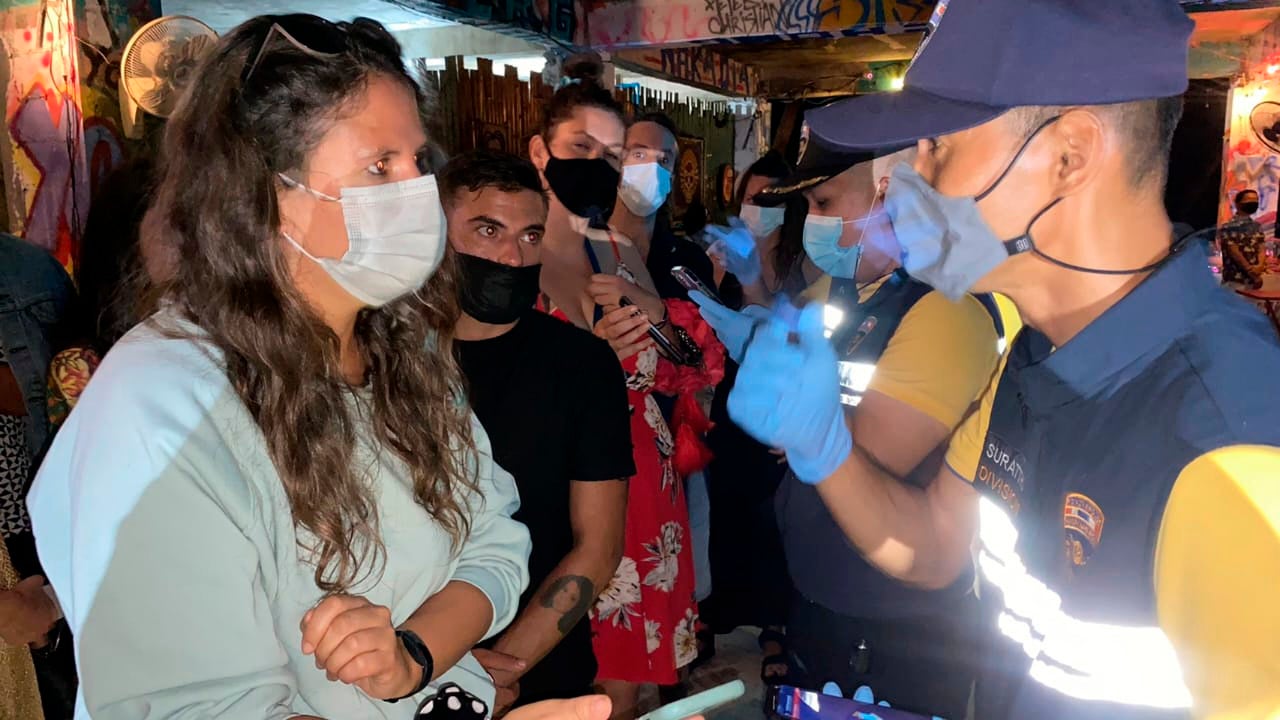 Thai immigration officers talk to people at a bar on Koh Phangan island, southern Thailand, on 26 January