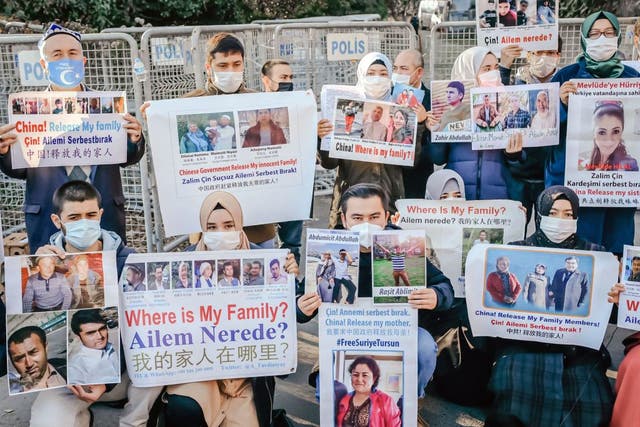 <p>Members of the Muslim Uighur community hold placards as they demonstrate in front of the Chinese consulate on 30 December, 2020</p>