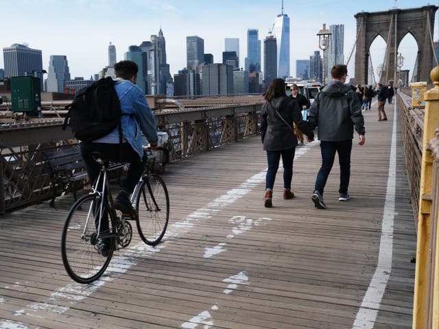 <p>Cyclists and pedestrians cross the Brooklyn Bridge on 12 February, 2020 in New York City</p>