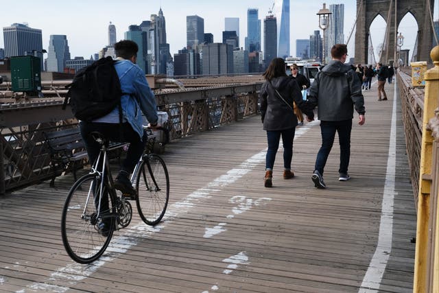 <p>Cyclists and pedestrians cross the Brooklyn Bridge on 12 February, 2020 in New York City</p>