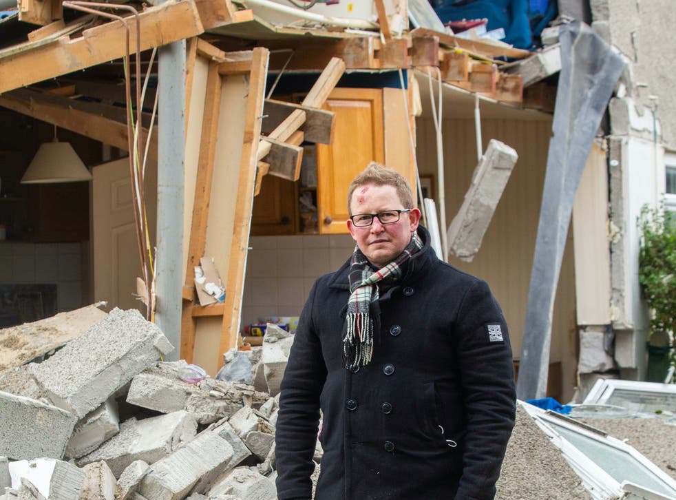 <p>Darren Cornish outside his parents’ ruined home in Bude </p>