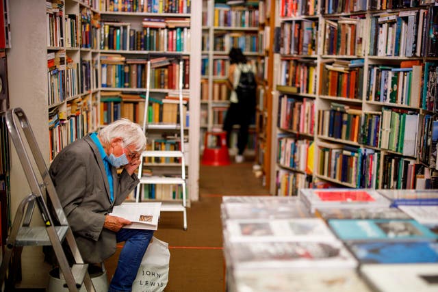 A man wearing a protective face mask browses books in Henry Pordes secondhand book shop in central London on 15 June 2020