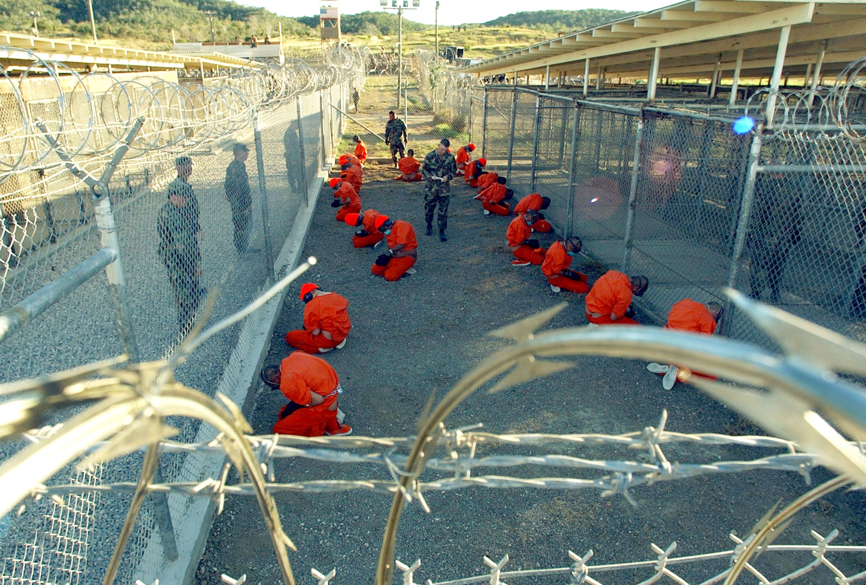 File: US Military Police guard Taliban and al Qaeda detainees in orange jumpsuits in January, 2002