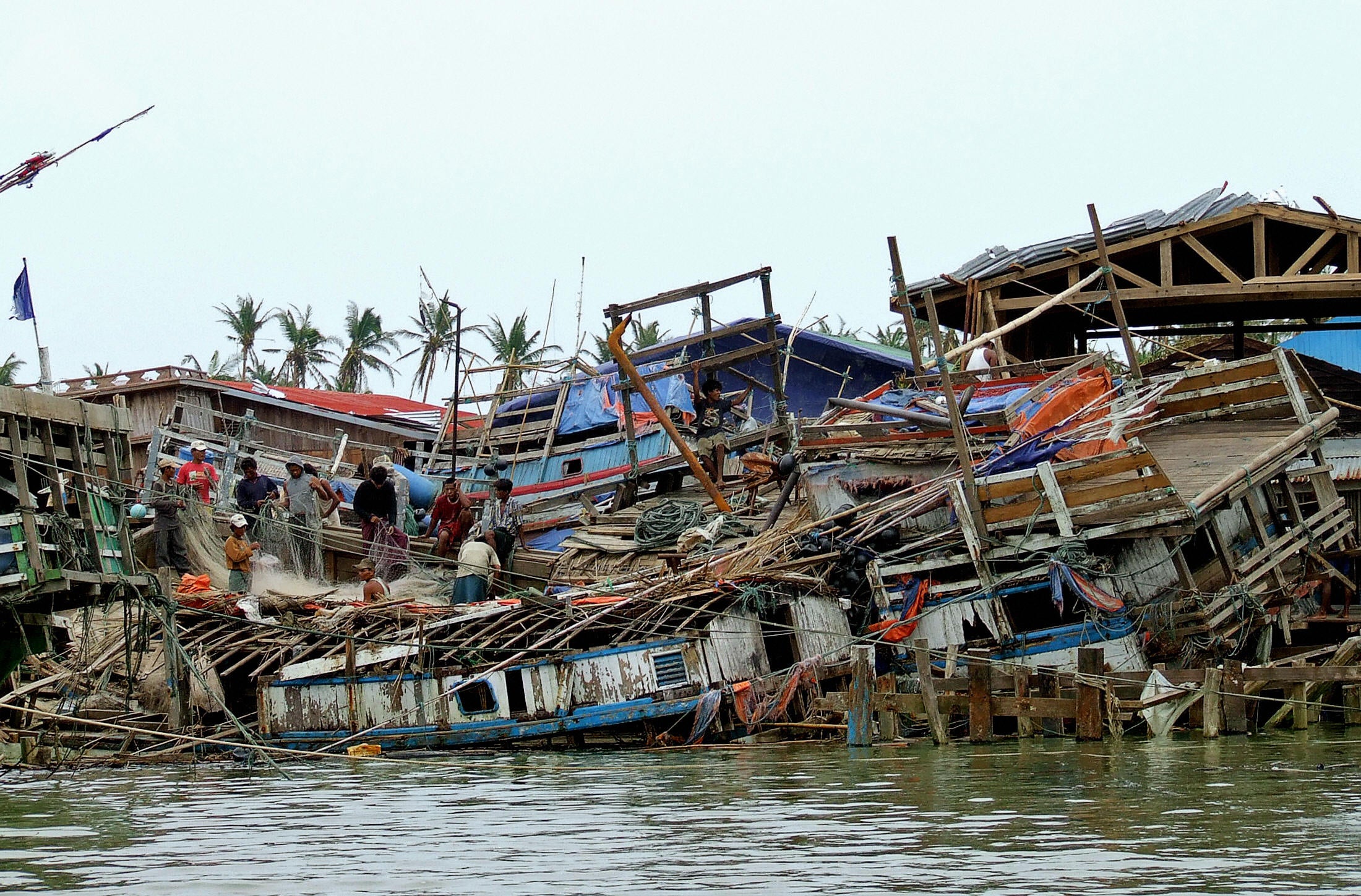Survivors stand on houses destroyed by Cyclone Nargis in Haing Gyi island in 2008