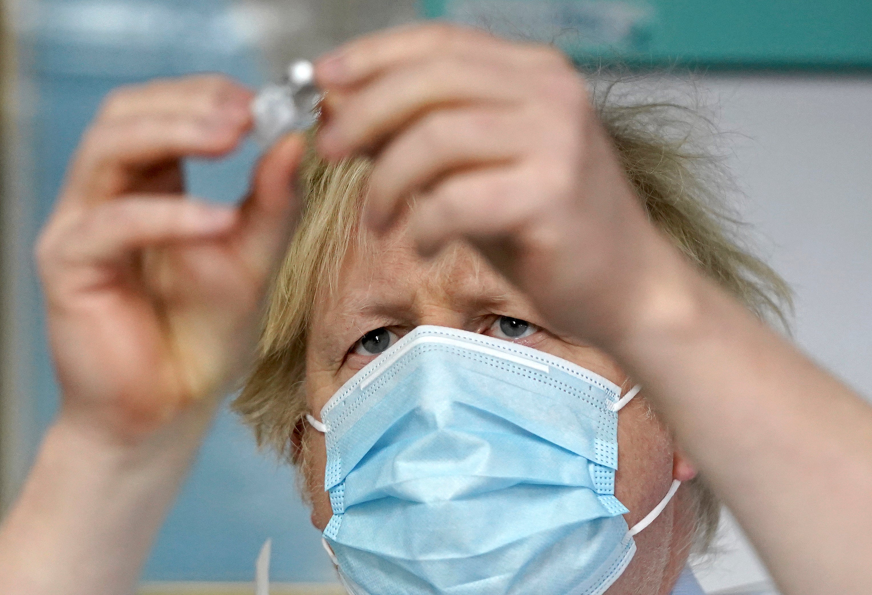 Boris Johnson examines a vaccine during a trip to a vaccination centre in Batley, West Yorkshire