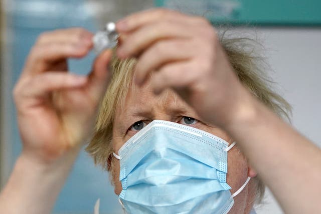 Boris Johnson examines a vaccine during a trip to a vaccination centre in Batley, West Yorkshire
