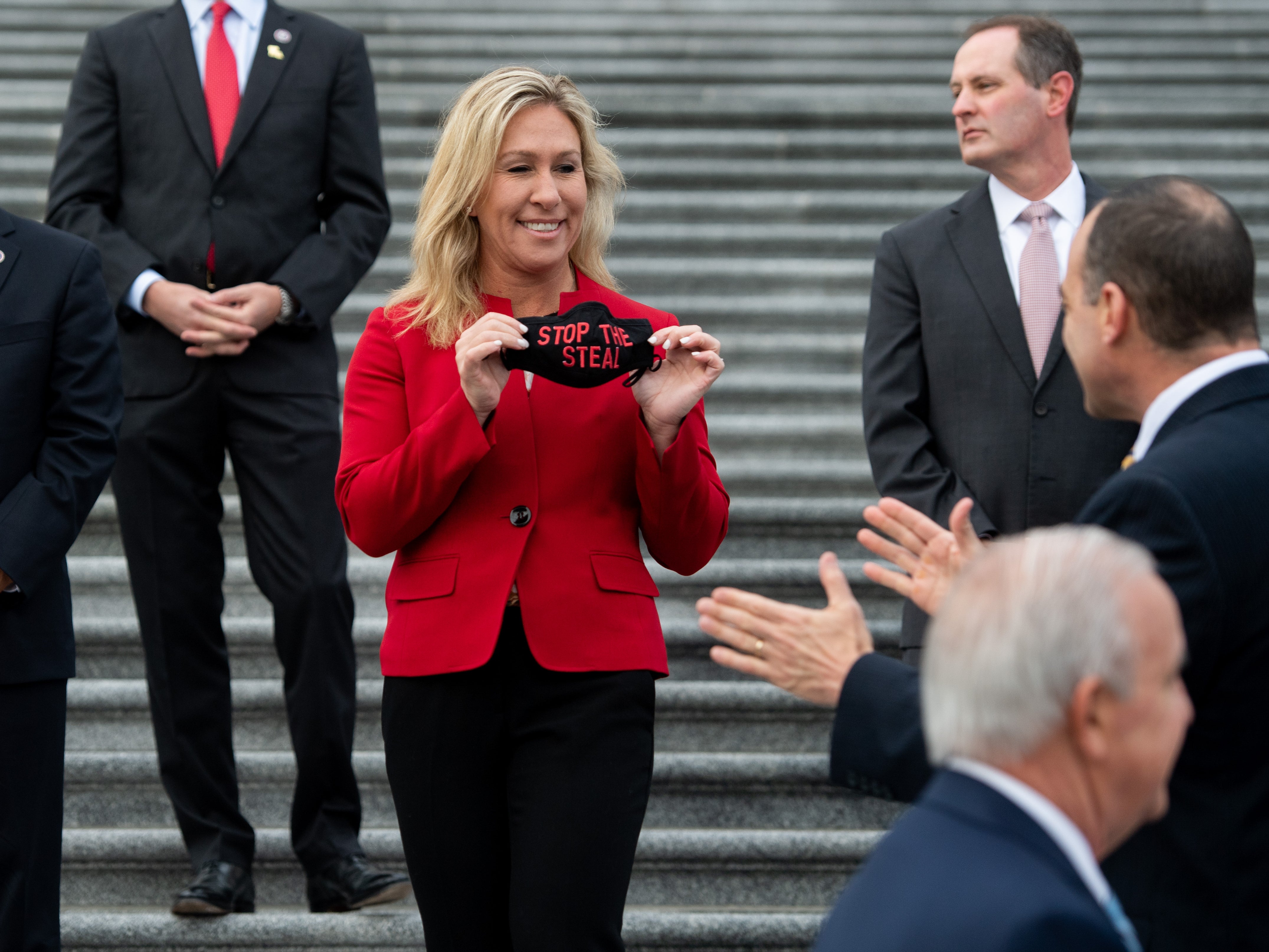 <p>Representative Marjorie Taylor Greene, Republican of Georgia, holds up a ‘Stop the Steal’ mask</p>
