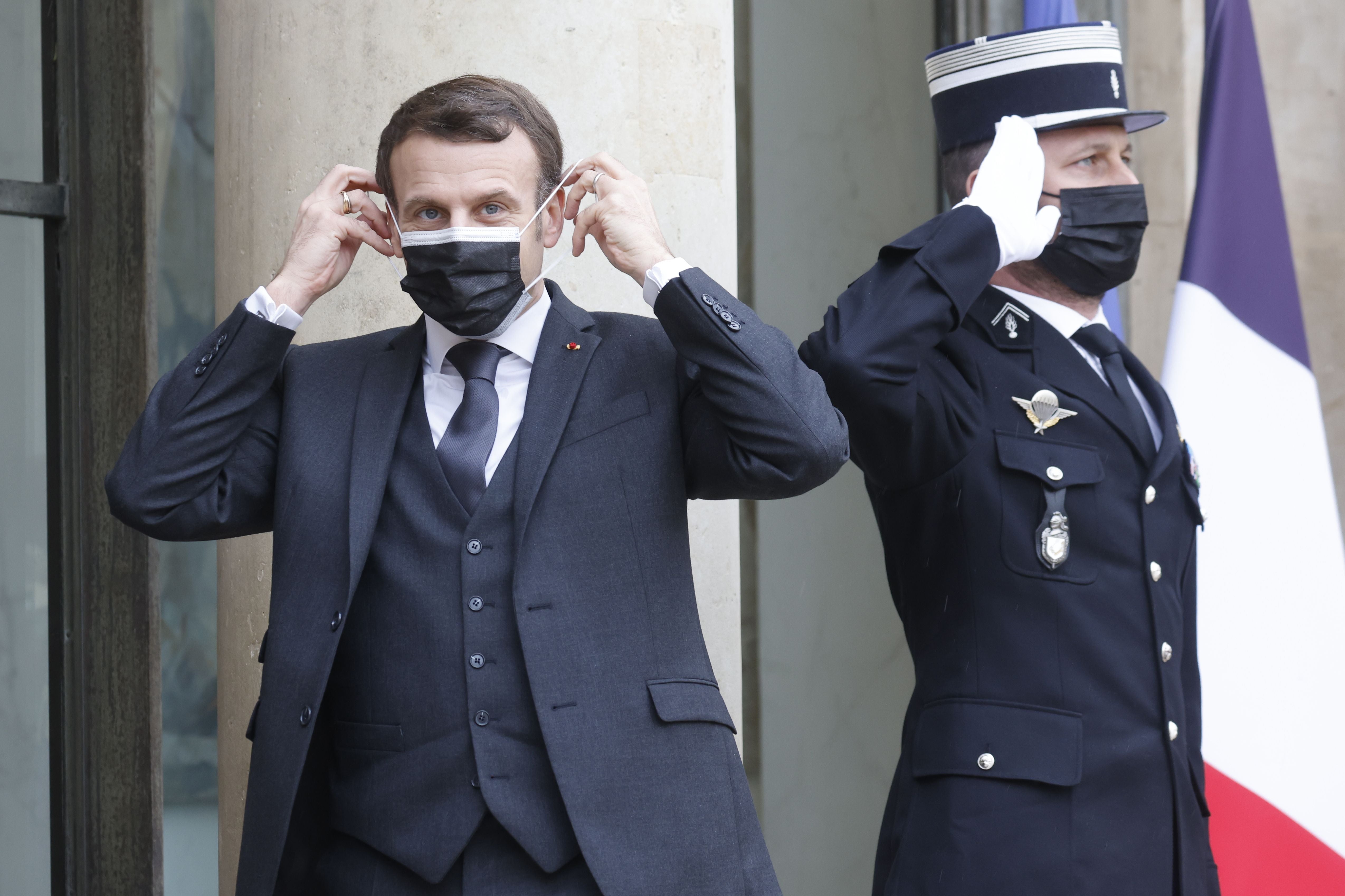 French President Emmanuel Macron adjusts his face mask on the sidelines of a working lunch on February 3, 2021 at The Elysee Presidential Palace in Paris