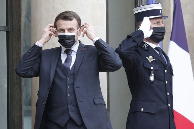 French President Emmanuel Macron adjusts his face mask on the sidelines of a working lunch on February 3, 2021 at The Elysee Presidential Palace in Paris