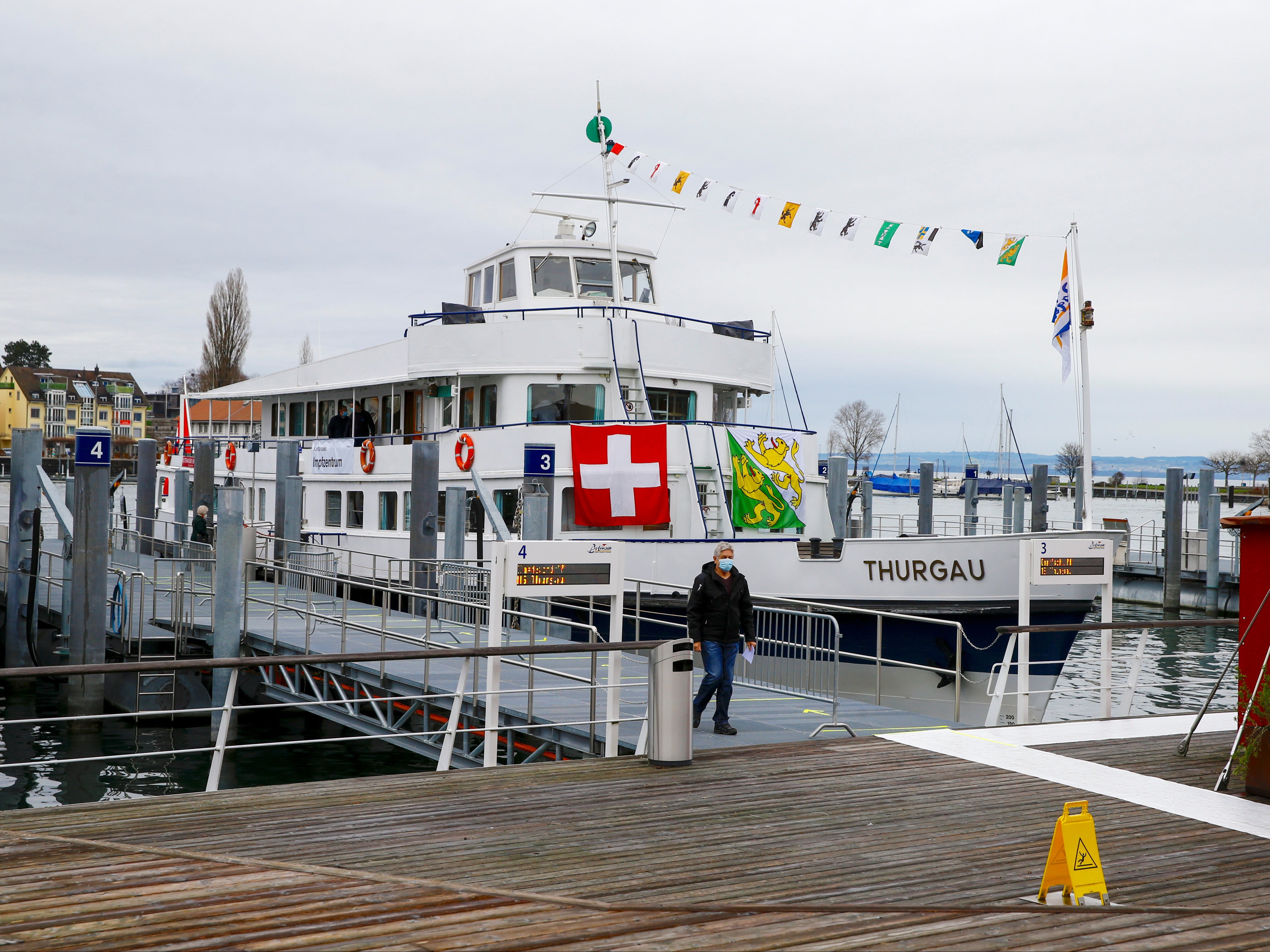 A man walks near a COVID-19 vaccination centre located aboard the MS Thurgau excursion boat in the harbour of Romanshorn on Lake Constance, Switzerland