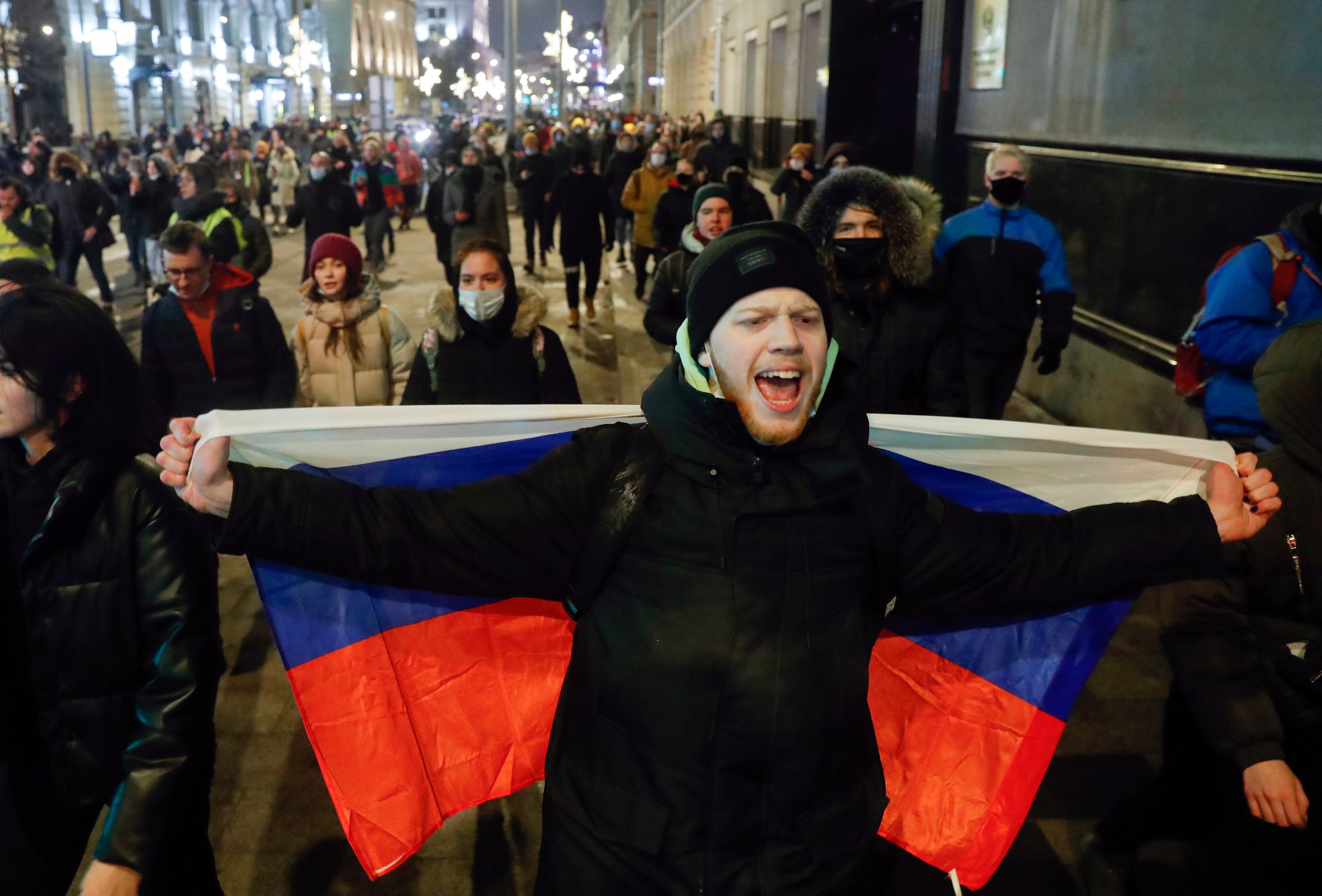 A demonstrator holds a Russian national flag during a protest after Russian opposition leader Alexei Navalny was sentenced to jail